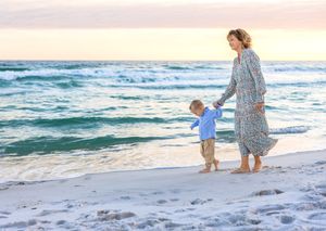 A family strolls along a sandy beach at sunset while waves gently roll onto the shore.