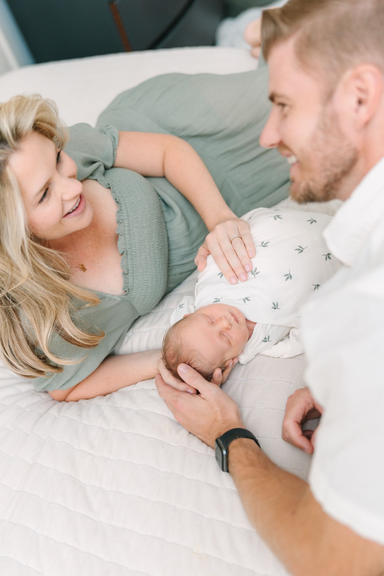 mom and dad laying on bed with newborn baby