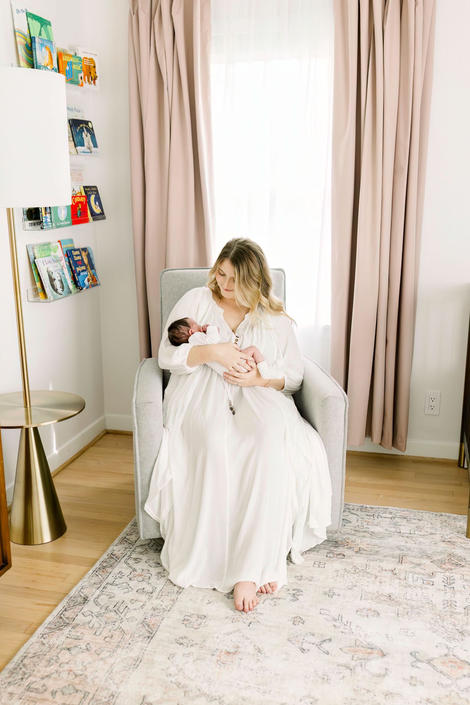 A peaceful nursery scene with white curtains and floating bookshelves as a mother holds her baby.