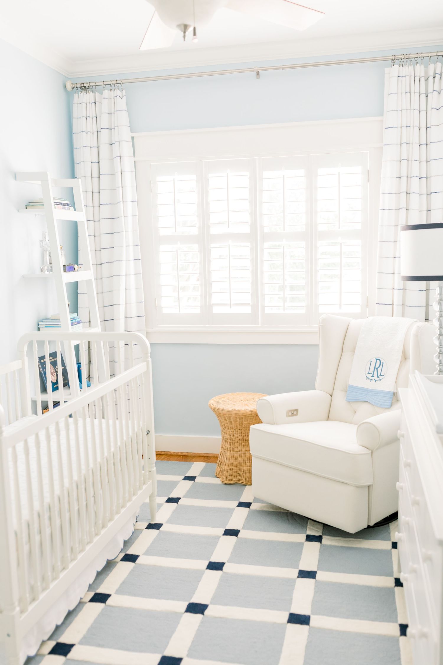 Modern nursery with white crib, geometric floor tiles, and blue walls.