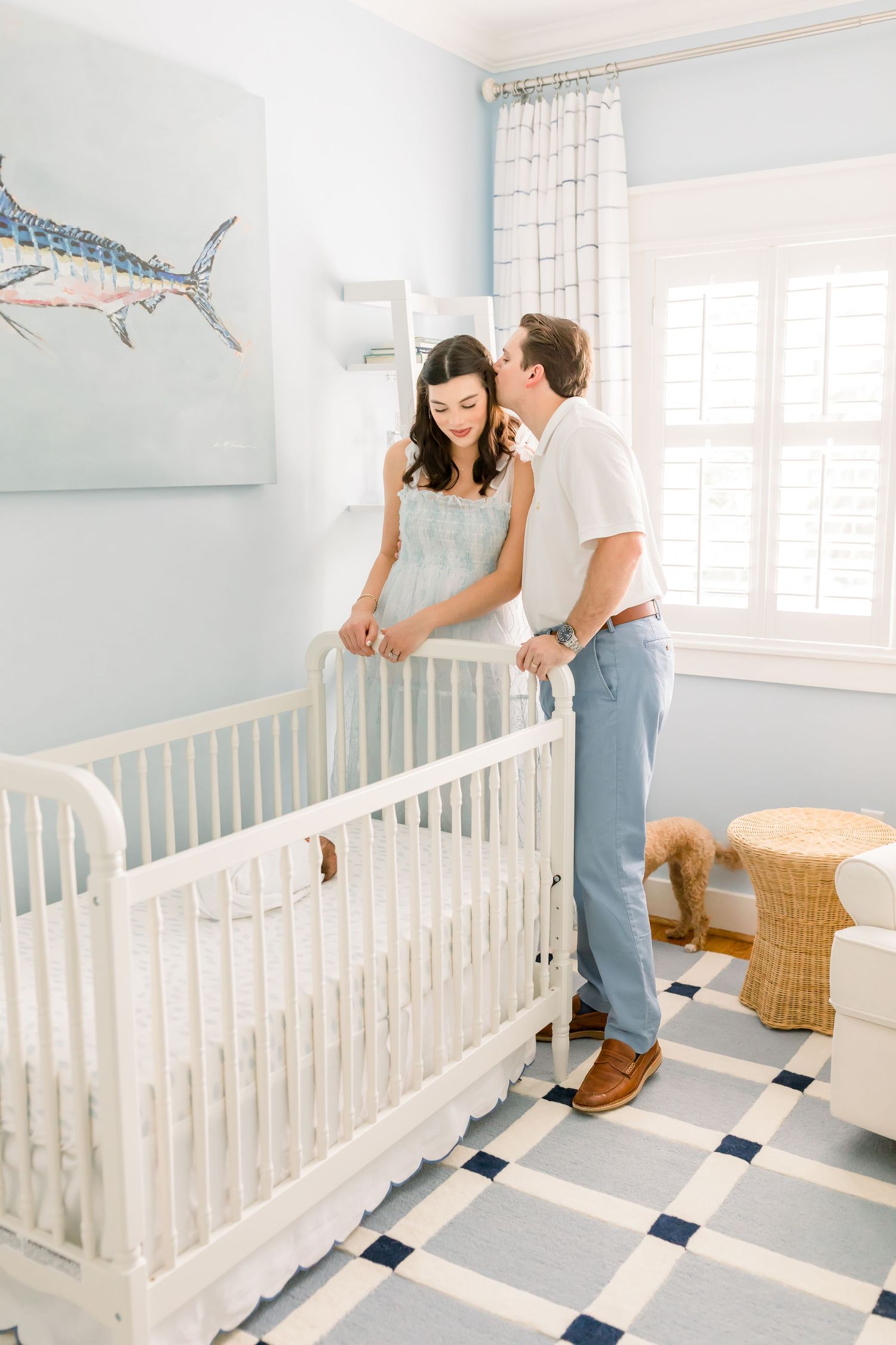 A nursery room with a white crib, blue walls, and a marlin art piece hanging above.
