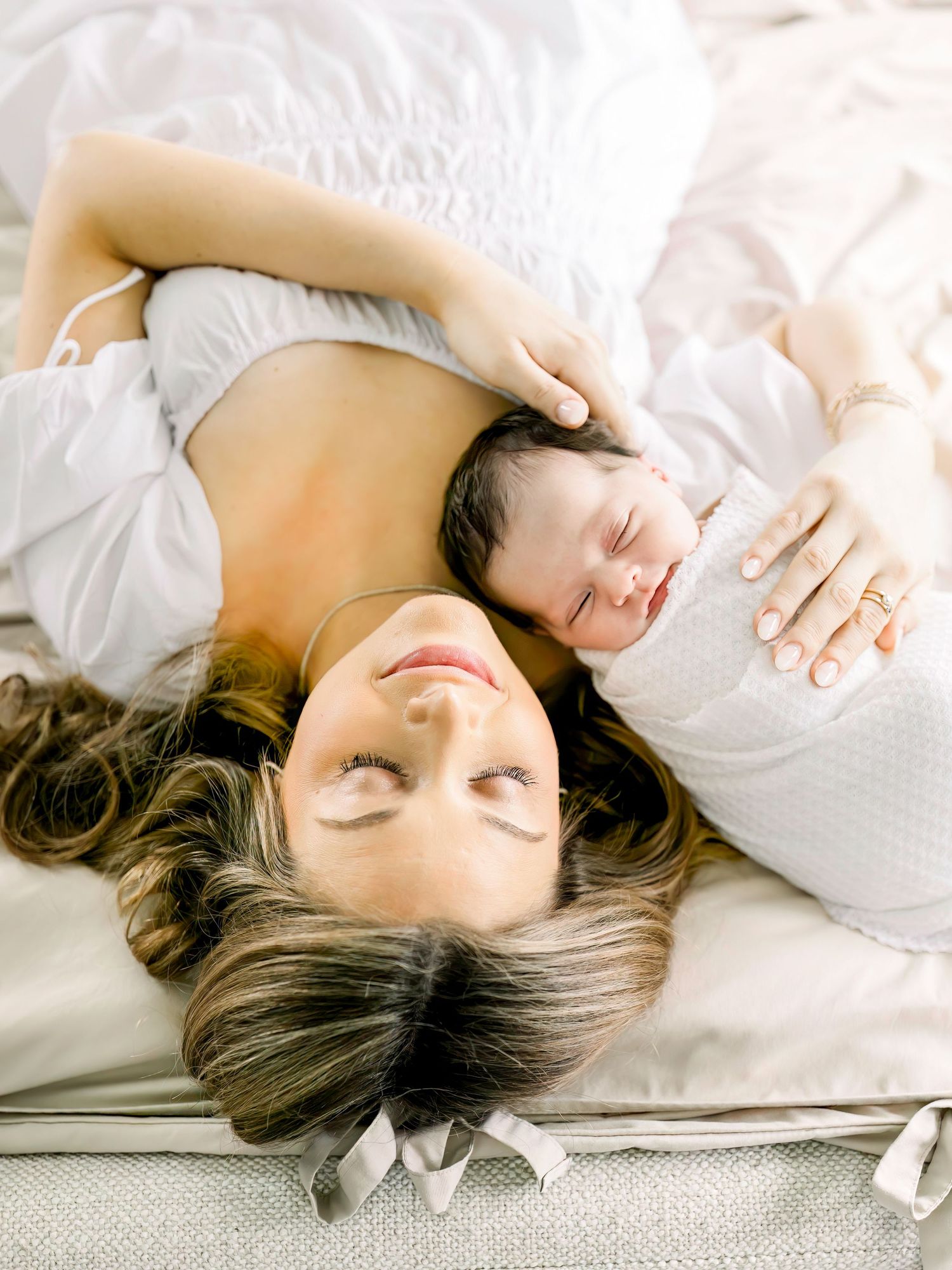 Intimate lifestyle portrait on gray tufted bed with soft natural lighting.