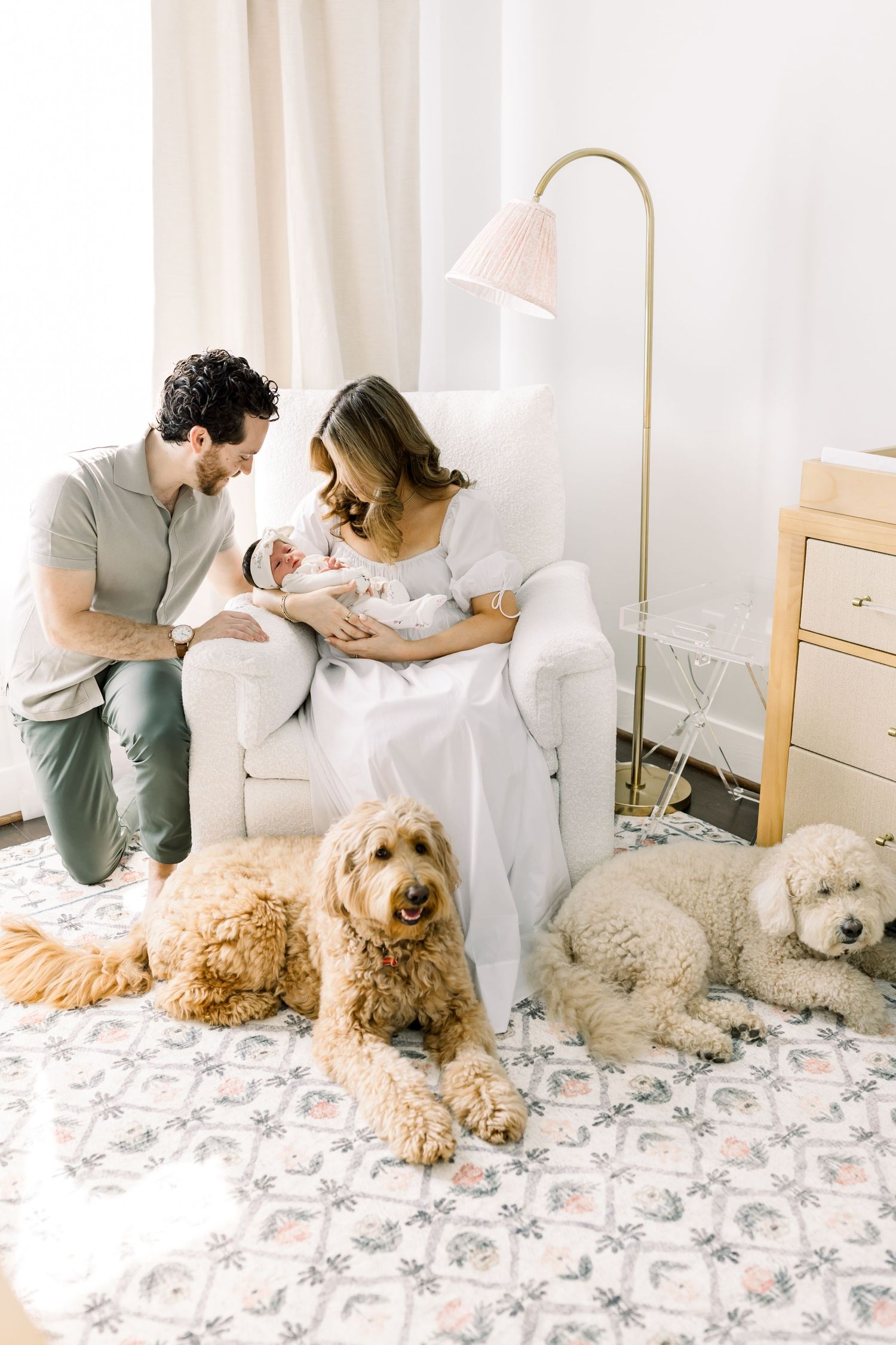 A family cuddles in a bright nursery with their two furry companions.