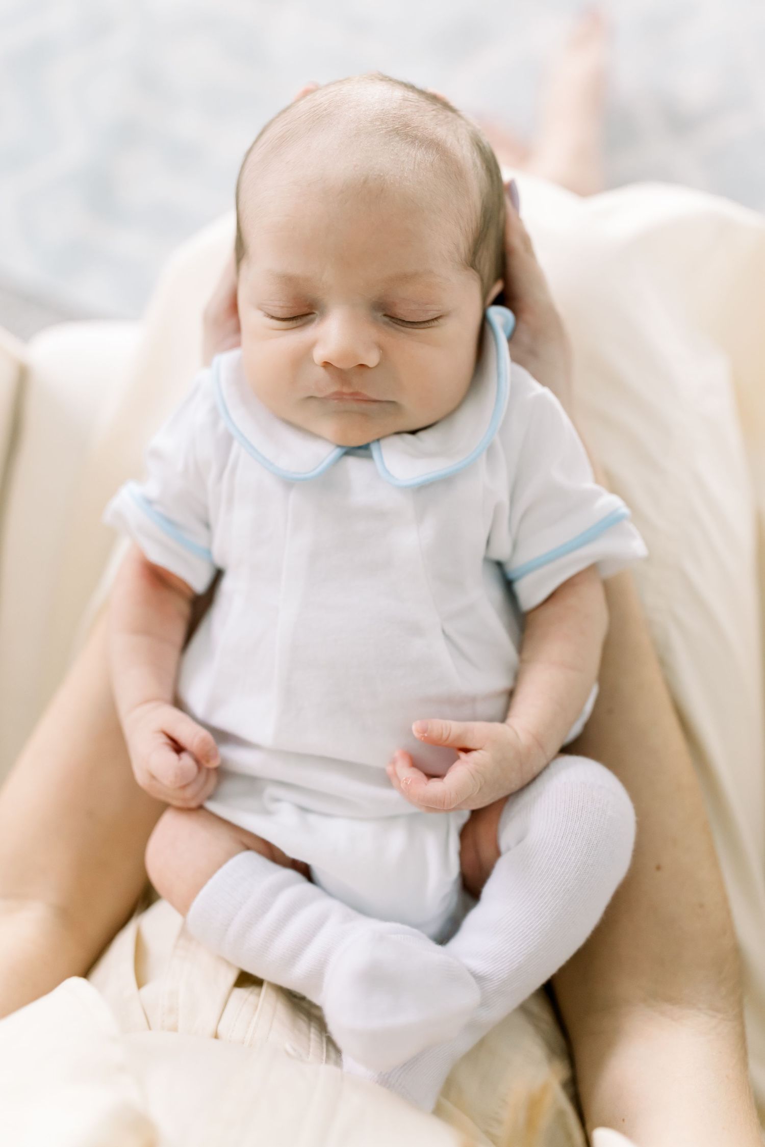 Sleeping baby in white and blue outfit resting peacefully.