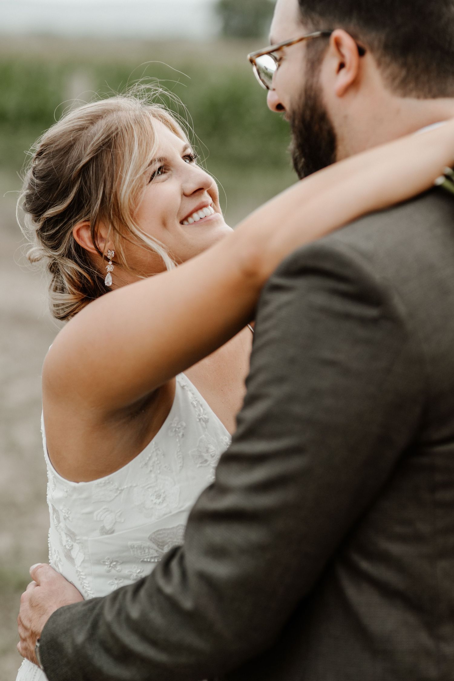 A couple shares an intimate embrace during their wedding, with the bride in white lace and groom in a dark suit.