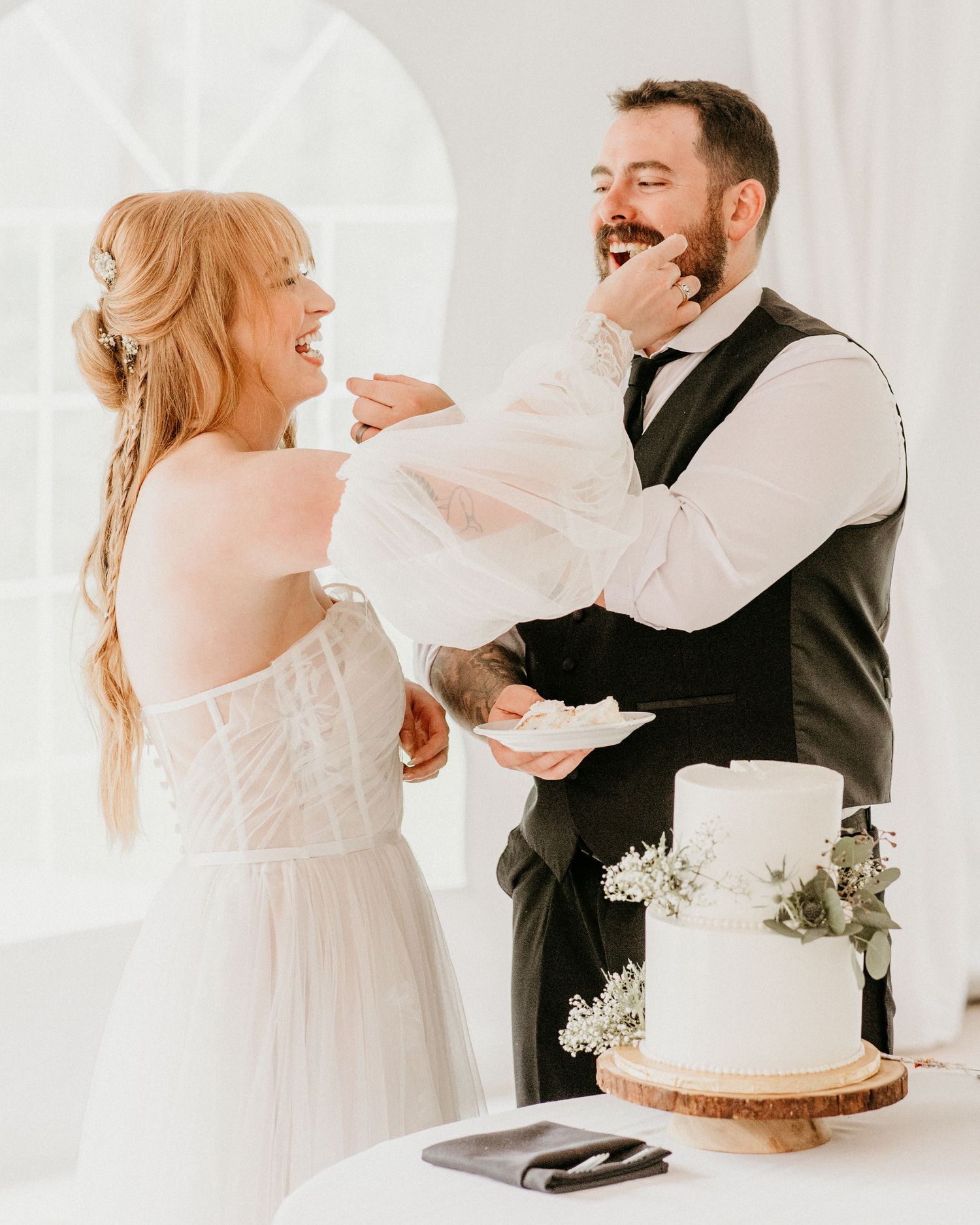 A couple sharing a joyful moment together while cutting their wedding cake at their reception celebration.