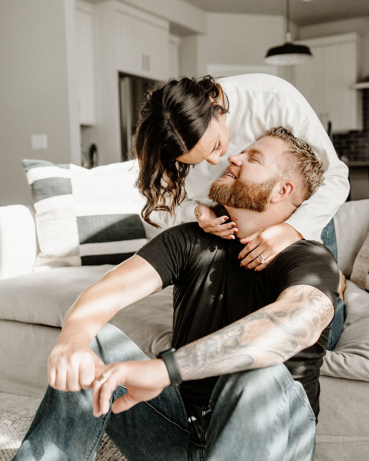 Intimate moment shared between couple on sofa showing affection in modern living room with natural lighting.