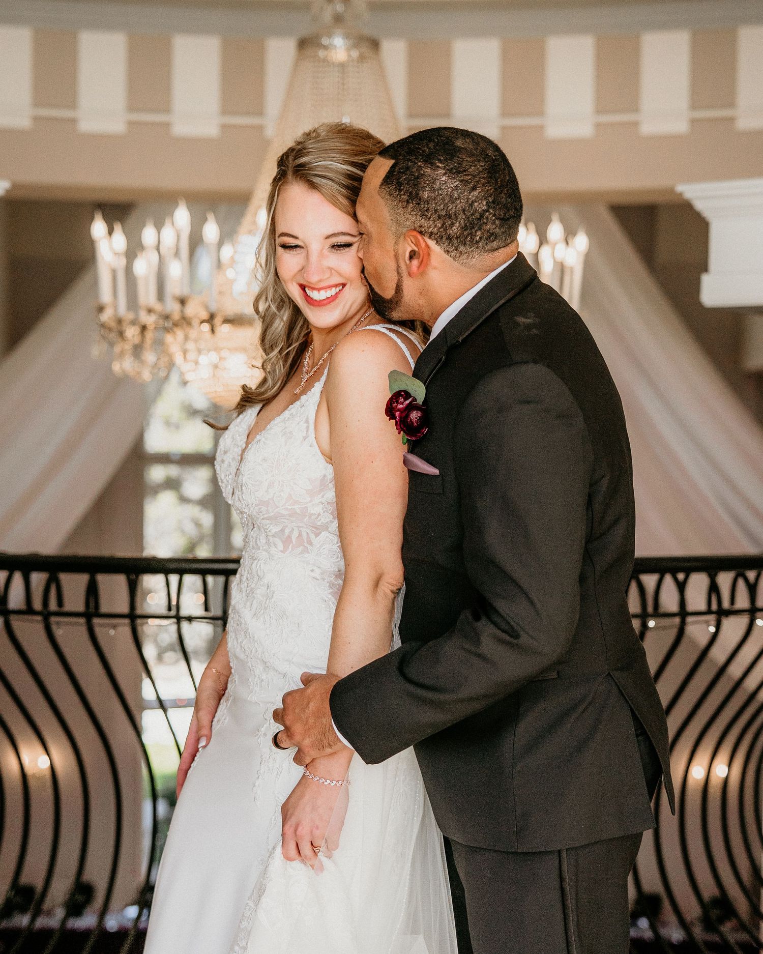 A romantic wedding scene showing a couple in formal attire sharing an intimate moment under an elegant crystal chandelier.