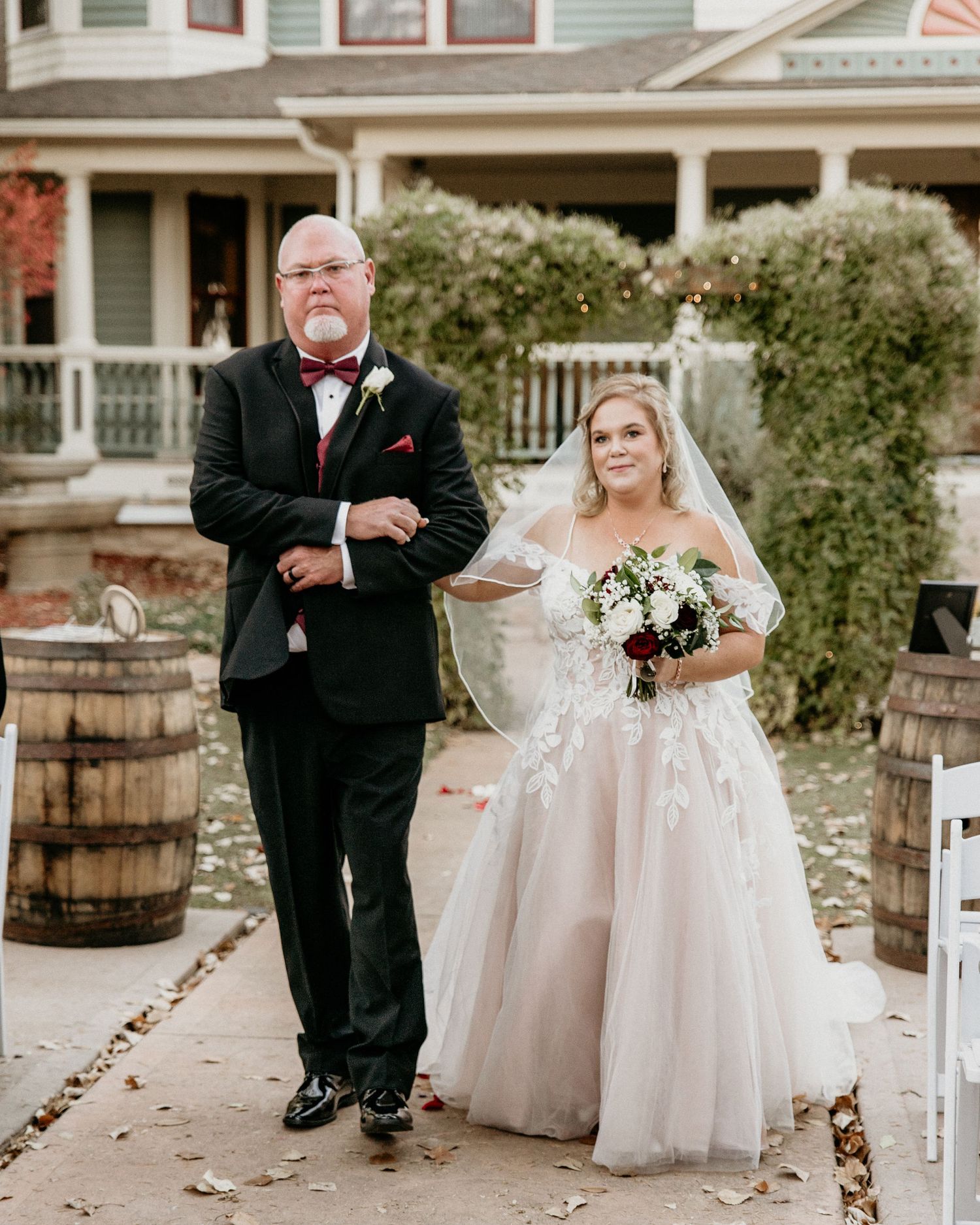A beautiful wedding scene on steps with rustic wooden barrels, featuring a formal dressed couple in wedding attire.