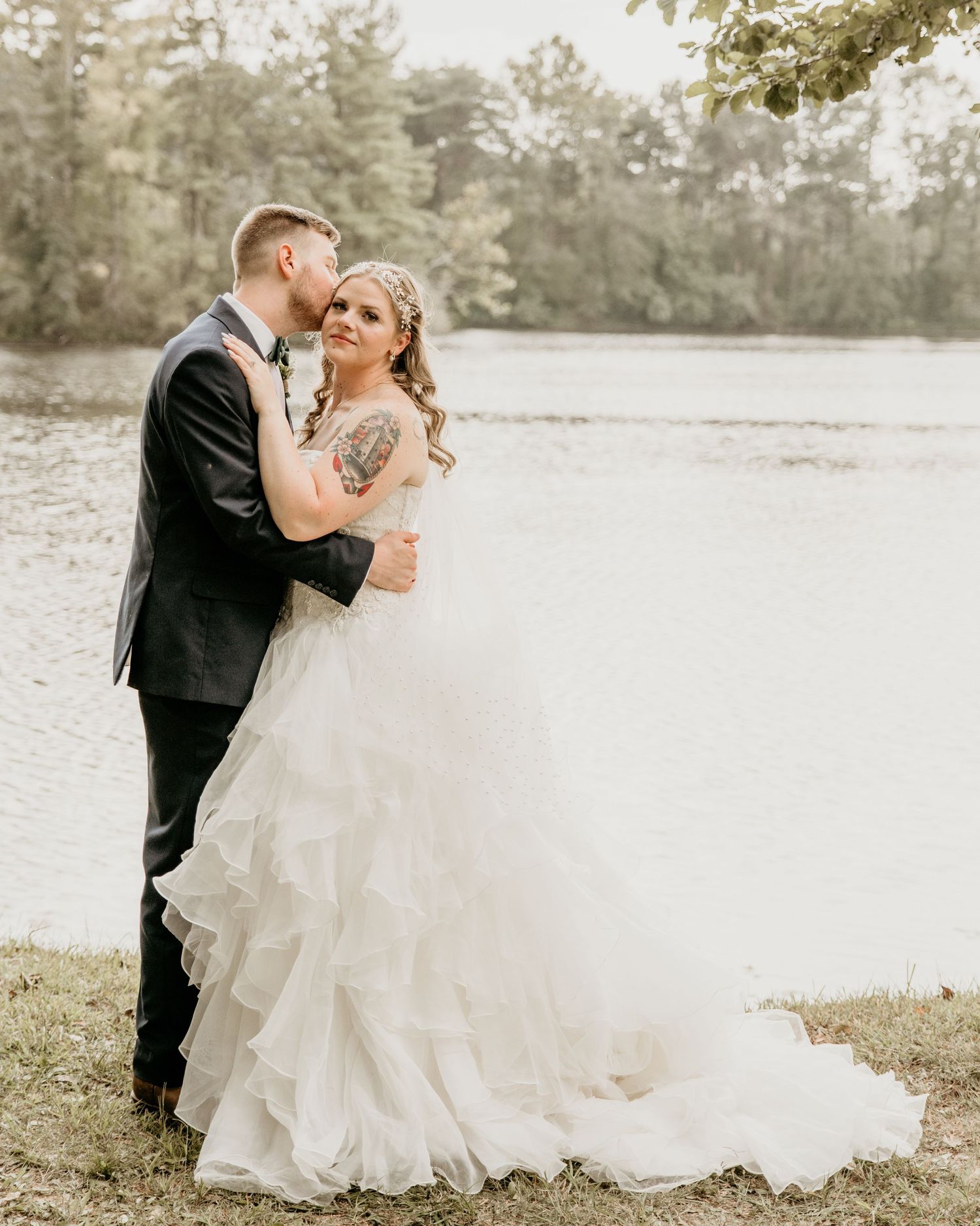 Intimate lakeside wedding portrait with couple embracing against a misty water backdrop.