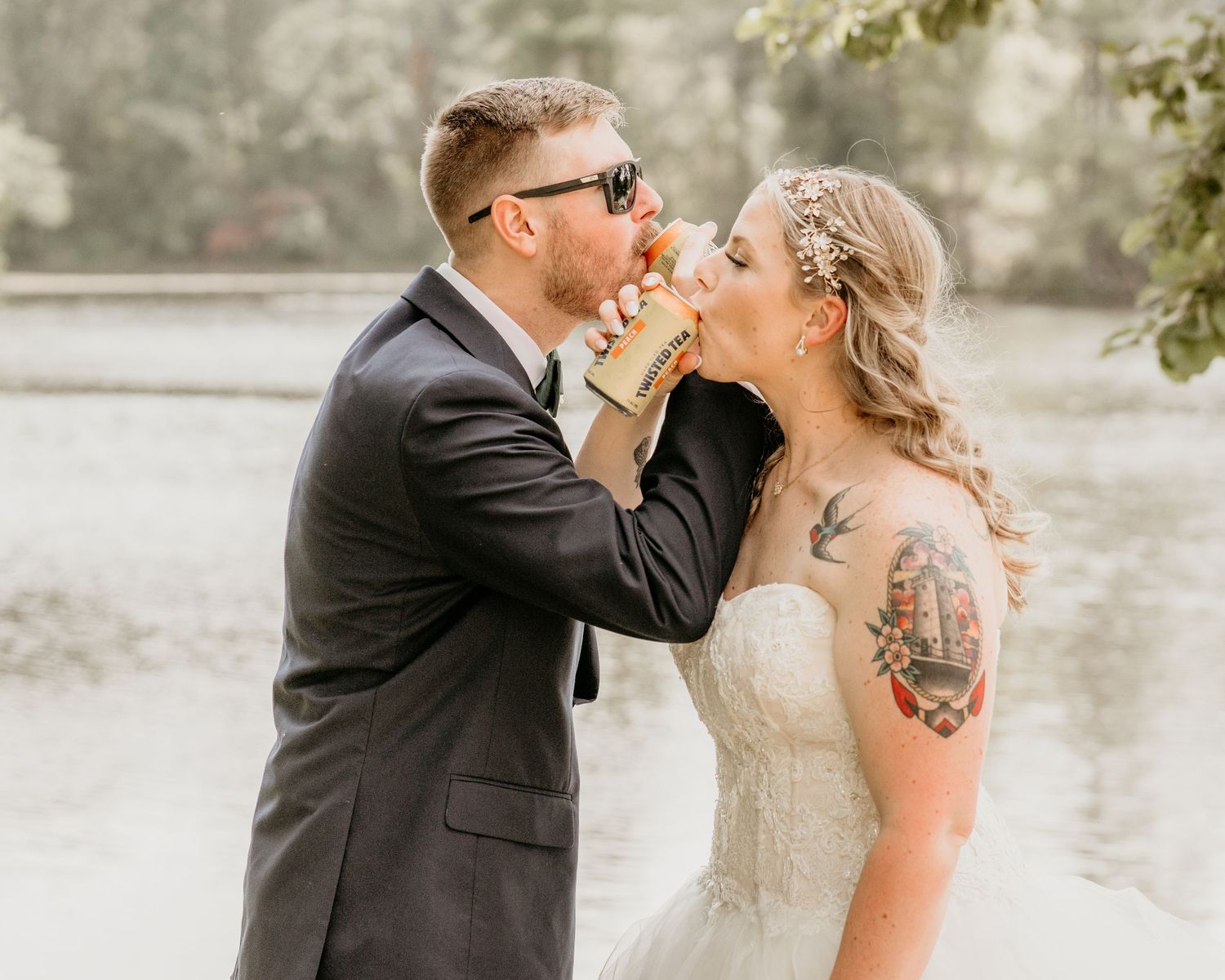 A bride and groom share an intimate moment by a misty lake while dressed in wedding attire.