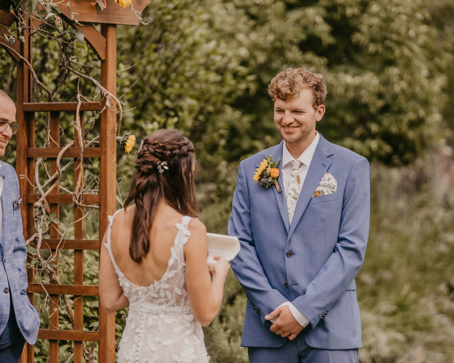 Intimate wedding ceremony moment under a wooden arch with floral decorations.