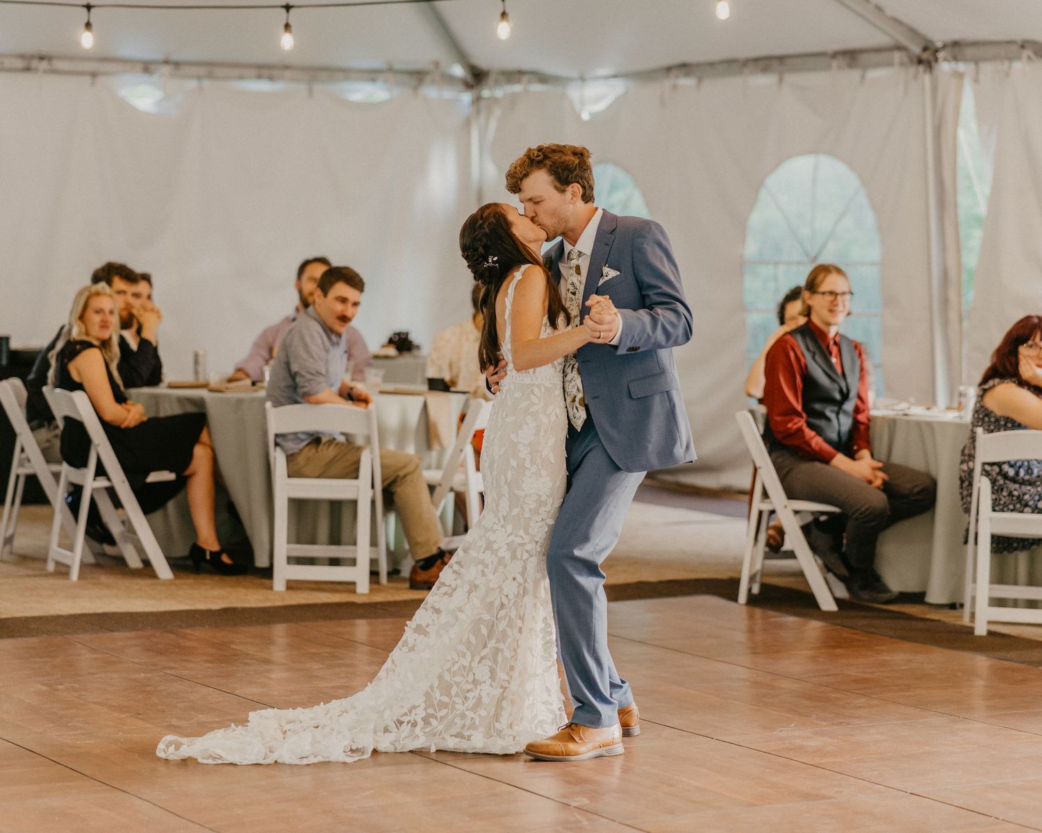 First dance under string lights in a white tent wedding reception.