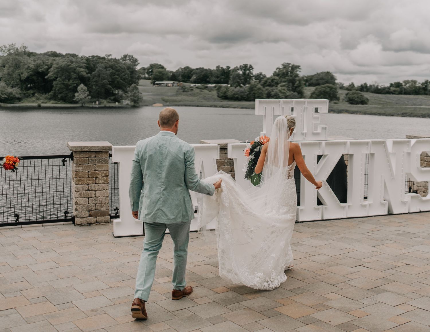 Wedding couple walking towards large white letters at outdoor venue.