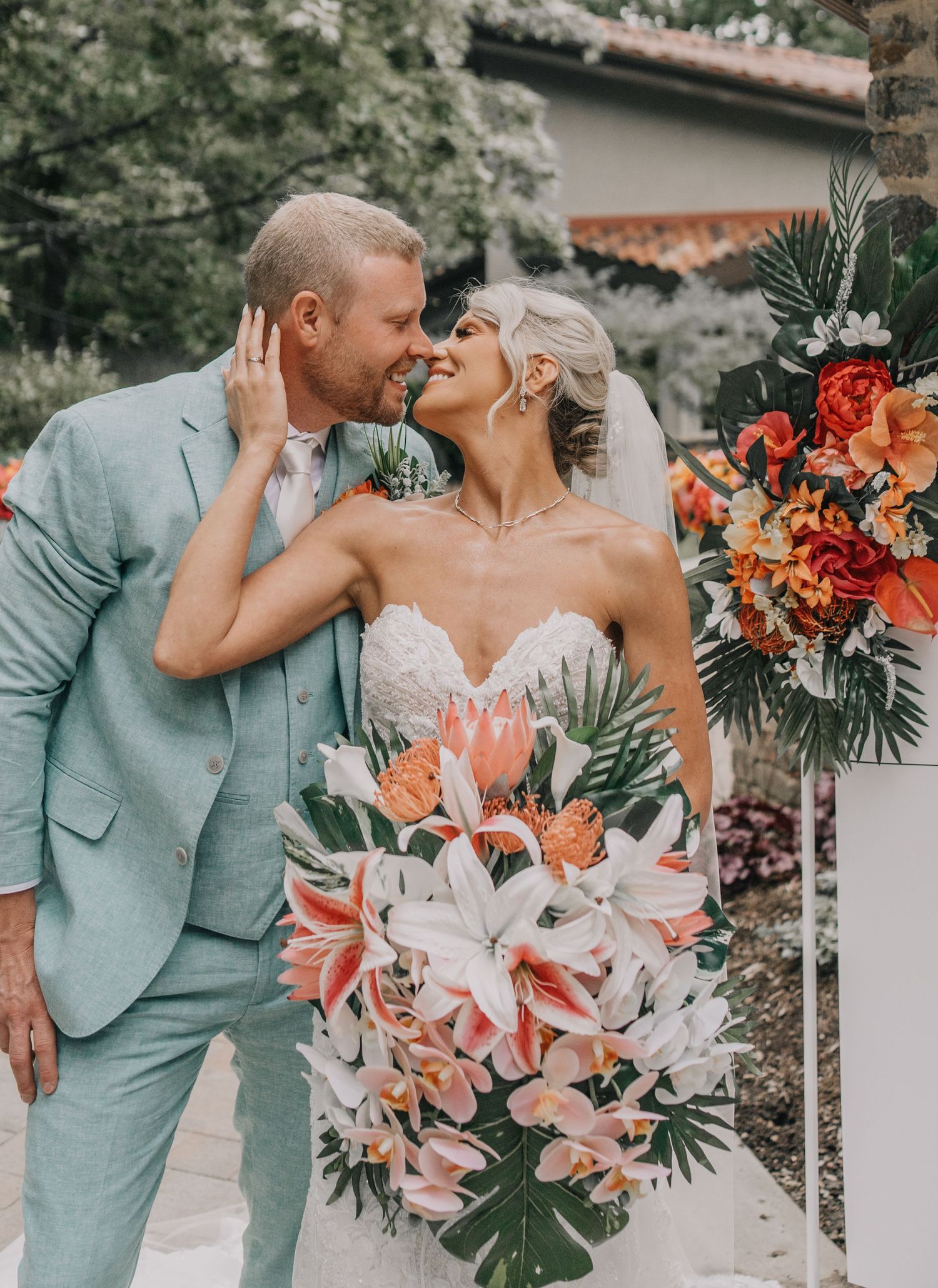 Romantic wedding moment captured with coral and white bouquet against natural backdrop.