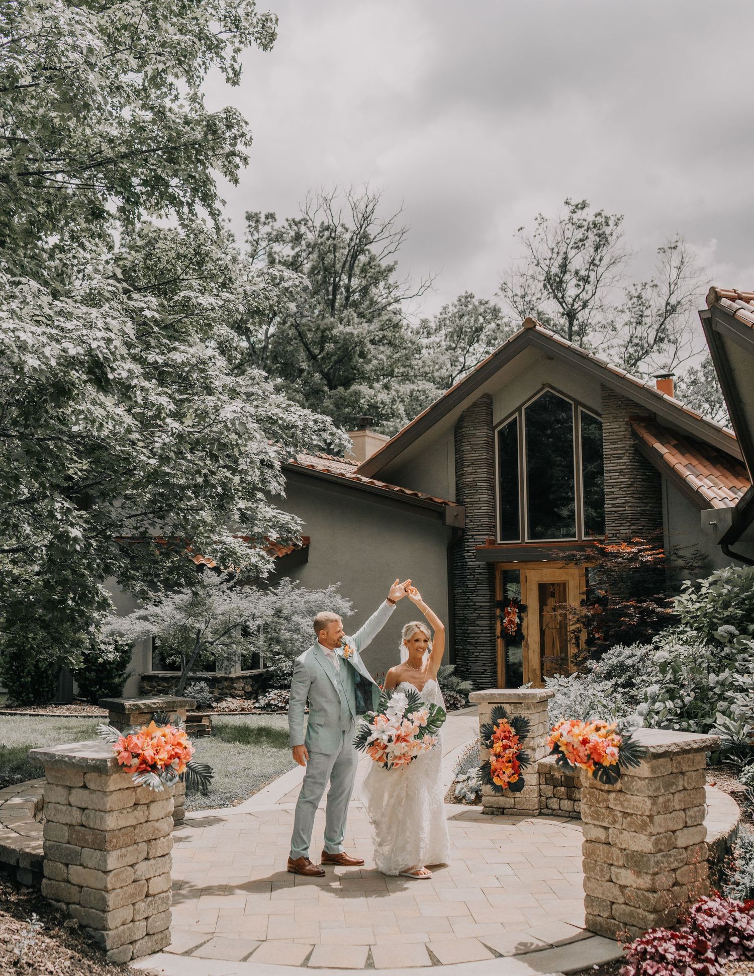 Joyful wedding celebration outside stone and wood architecture with coral floral decorations.
