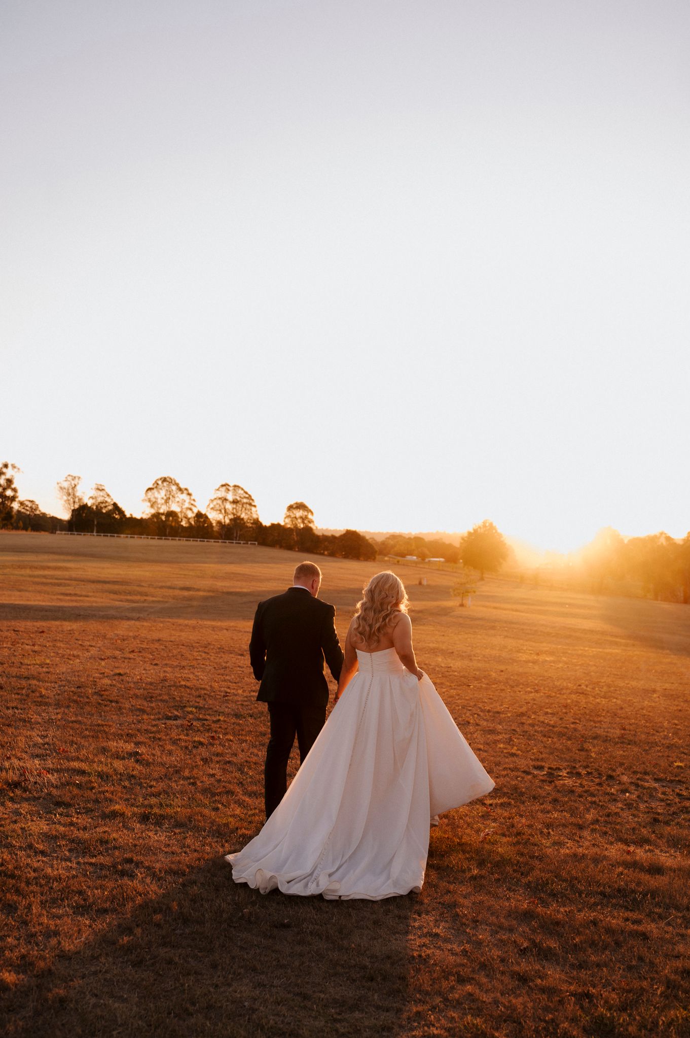 Romantic sunset silhouette of couple walking in a golden field.