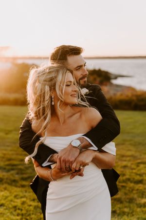 A romantic sunset wedding photo session in a grassy field near the coast.