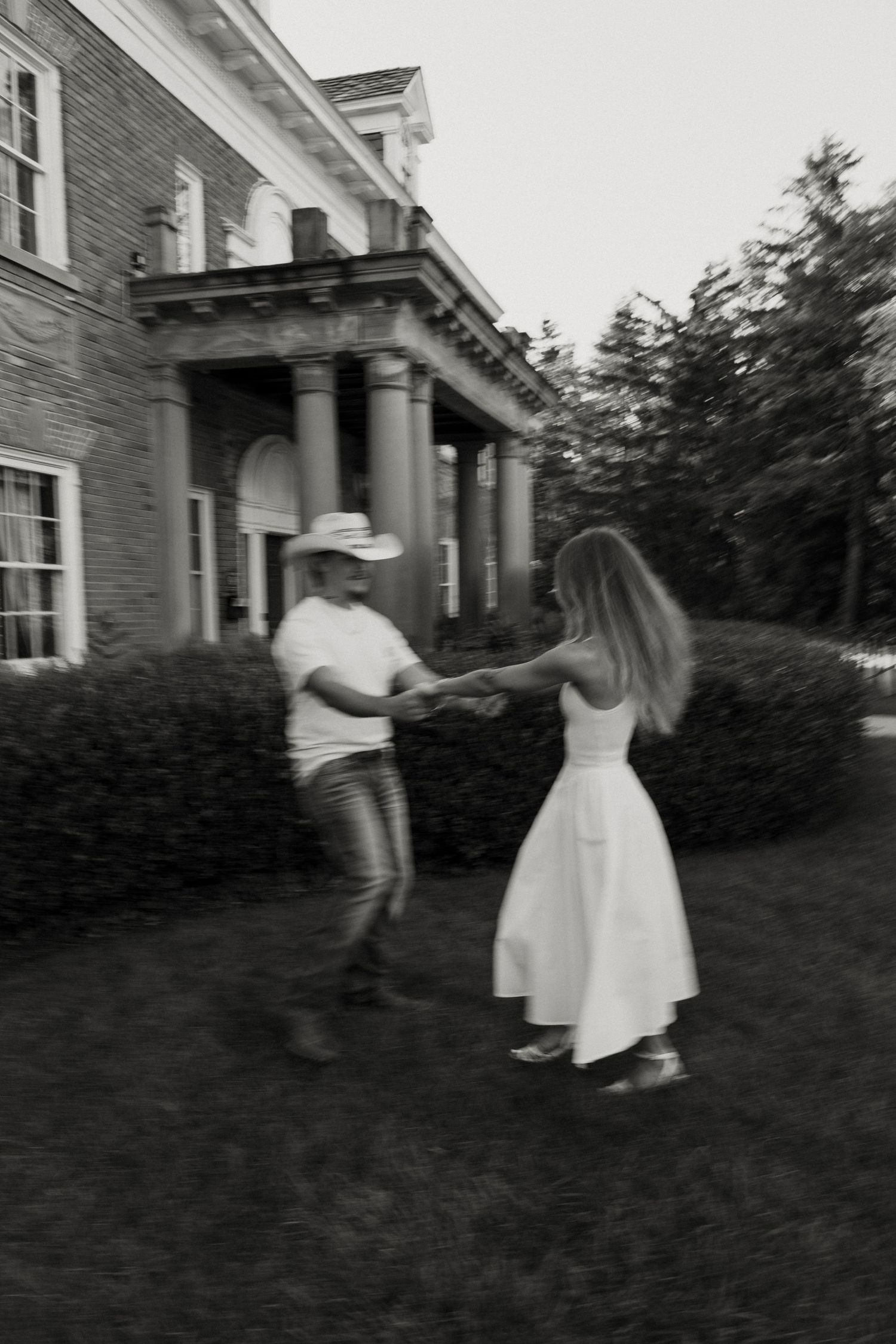 A blurred image of a couple walking on the lawn in front of a large, historic building. Fort Worth Texas wedding photographer. Western photo