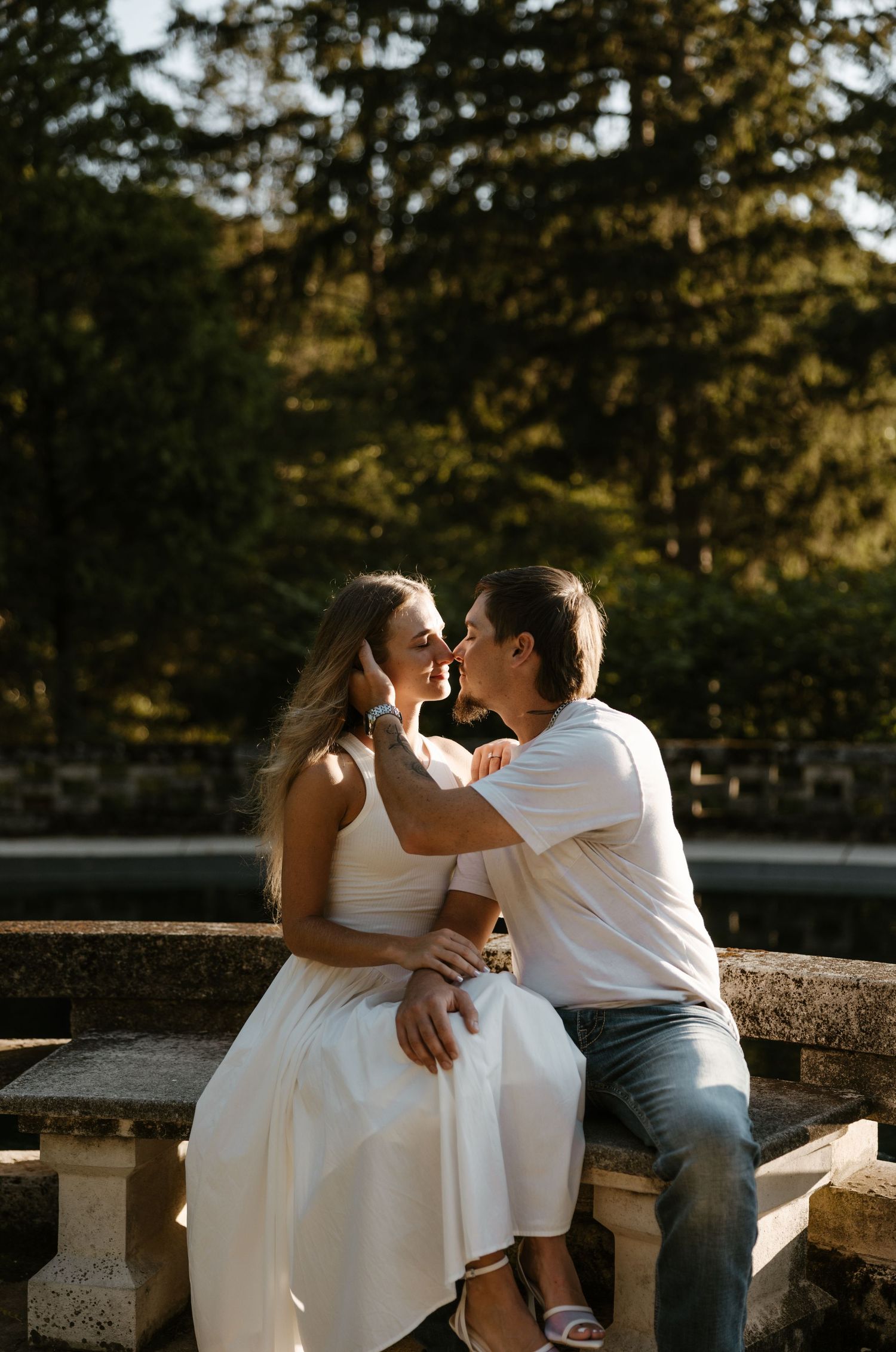 A bride and groom embracing in a romantic outdoor setting with trees in the background. Fort Worth Texas wedding photographer.