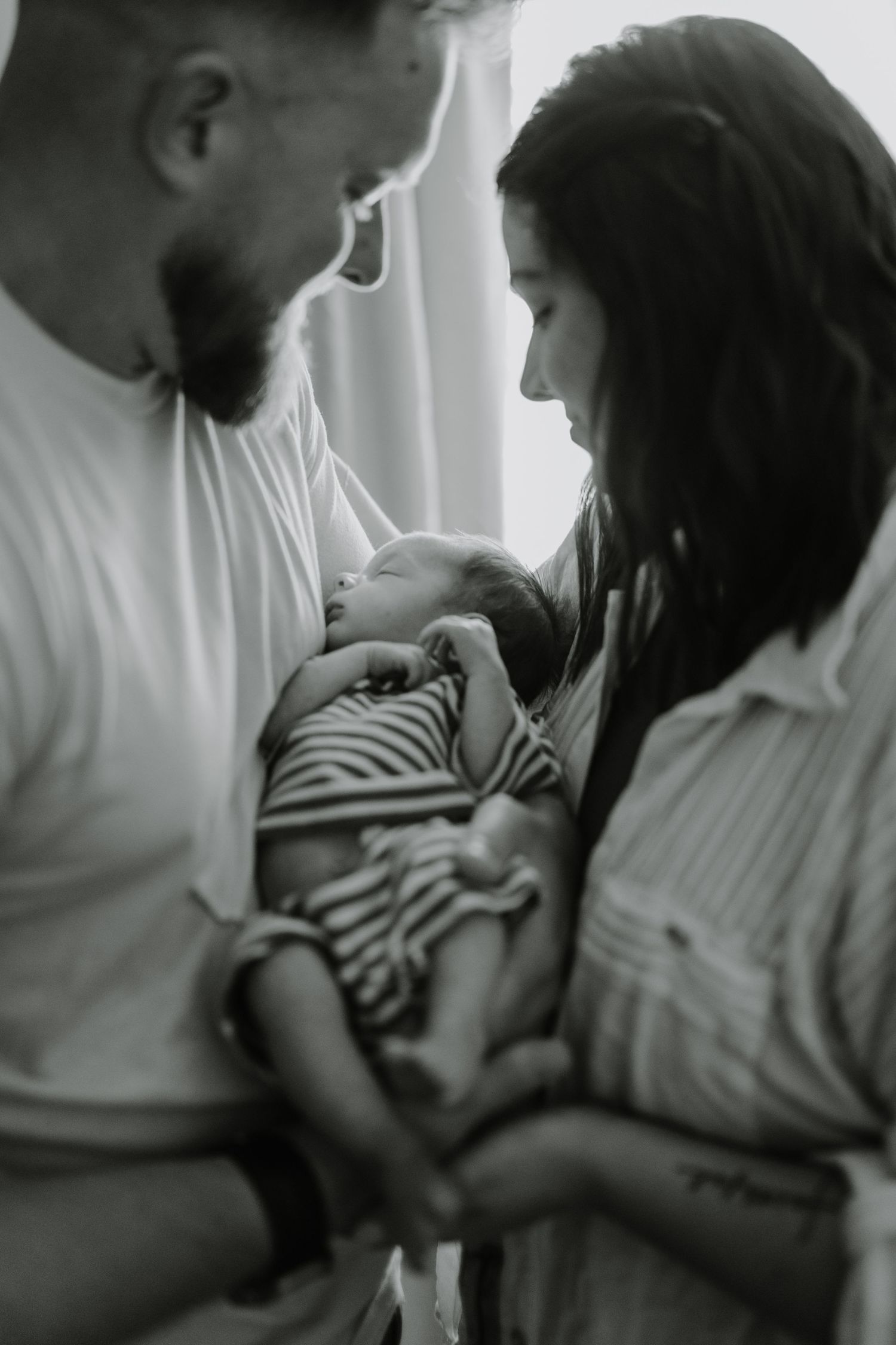 Intimate family moment captured in soft black and white tones.