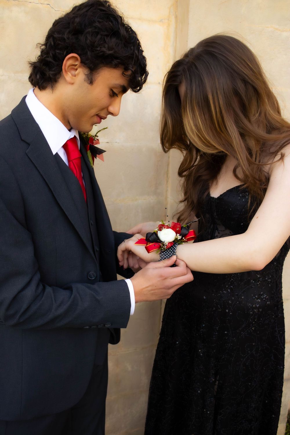 A couple in formal attire sharing a corsage moment at prom.