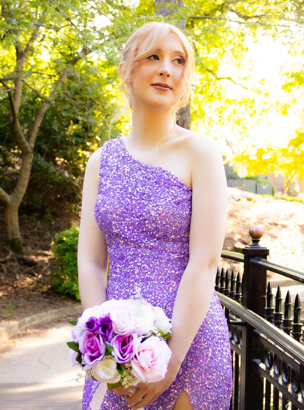 Formal portrait in purple sparkly dress holding bouquet outdoors.