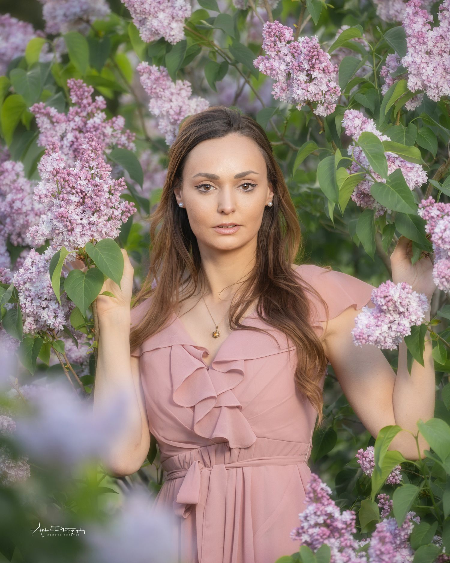 Romantic portrait among blooming lilac bushes with soft natural lighting.