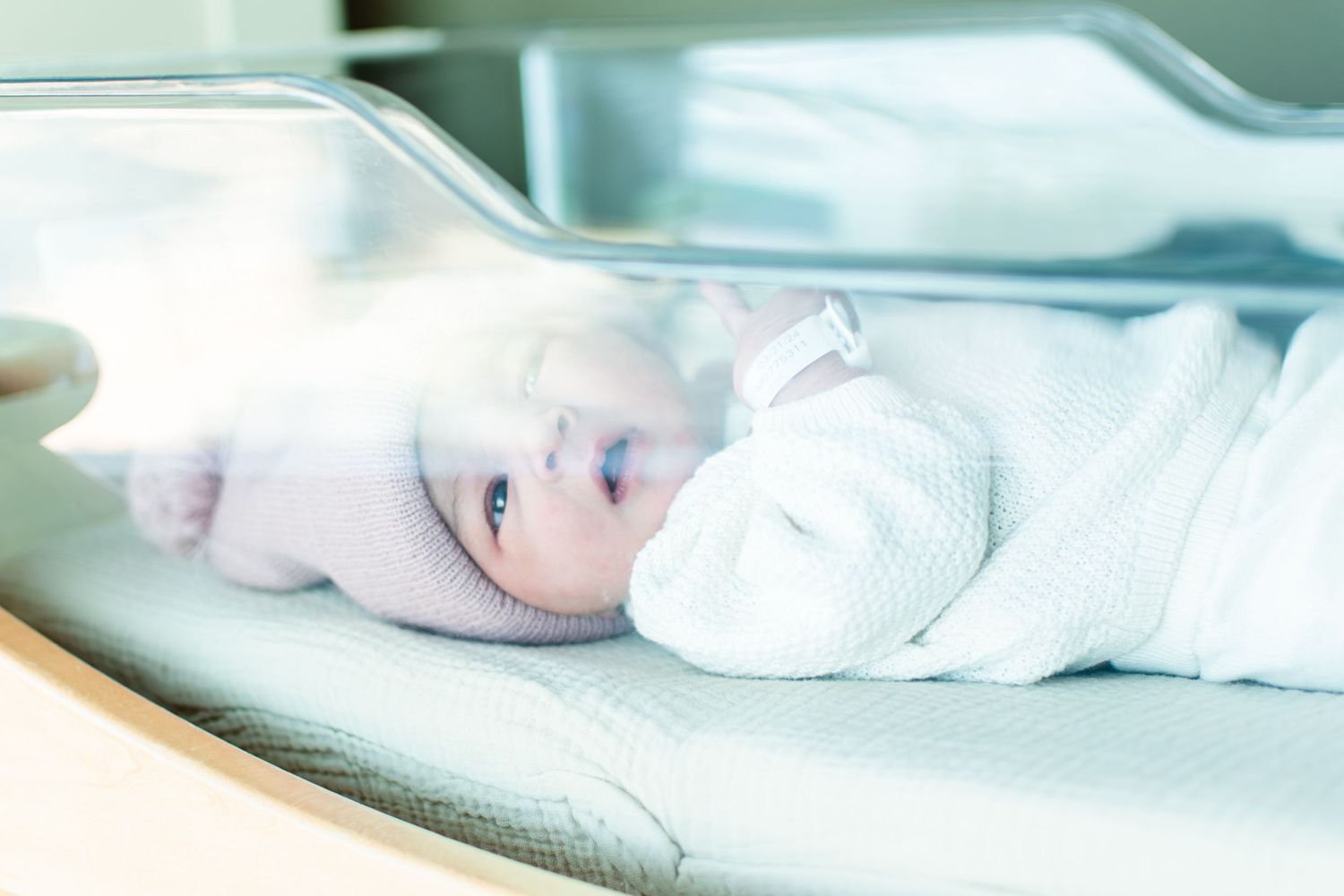 Newborn baby wrapped in white lying on a medical examination table.