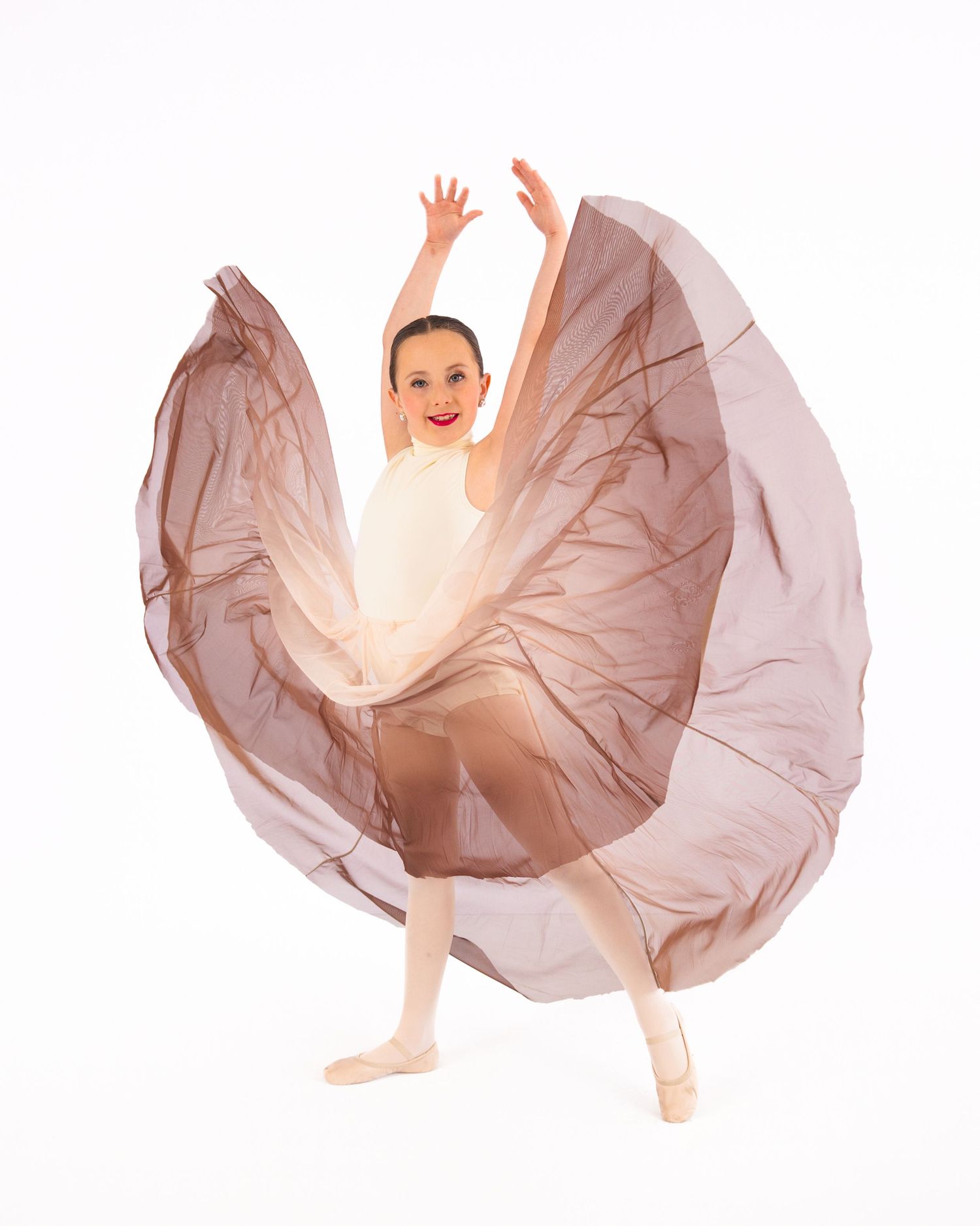 Studio portrait of a person in a white dress shirt kneeling next to a young dancer in a sparkly pink tutu dress.