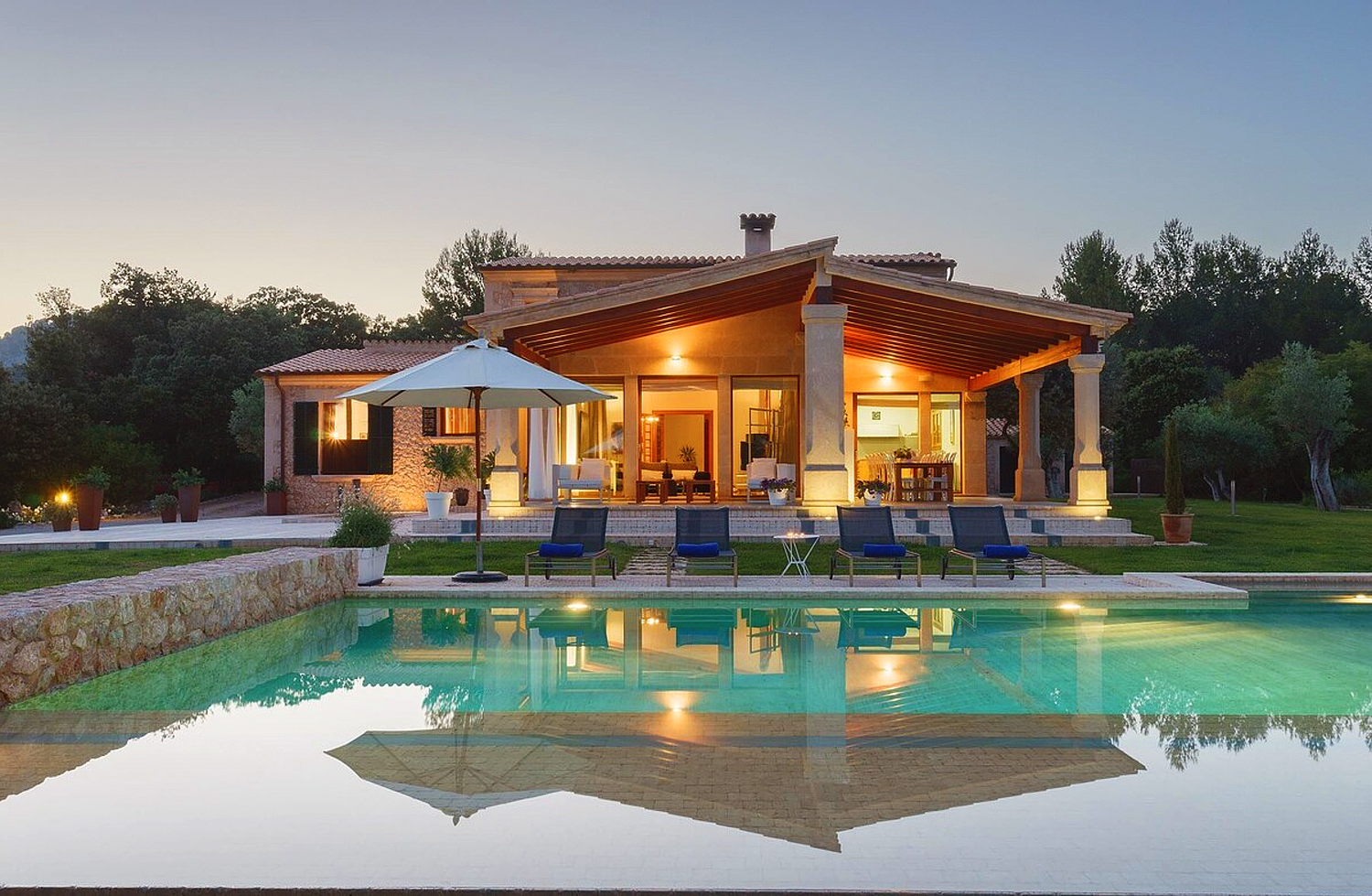 Luxury villa with infinity pool reflecting warm evening lights and contemporary architecture.