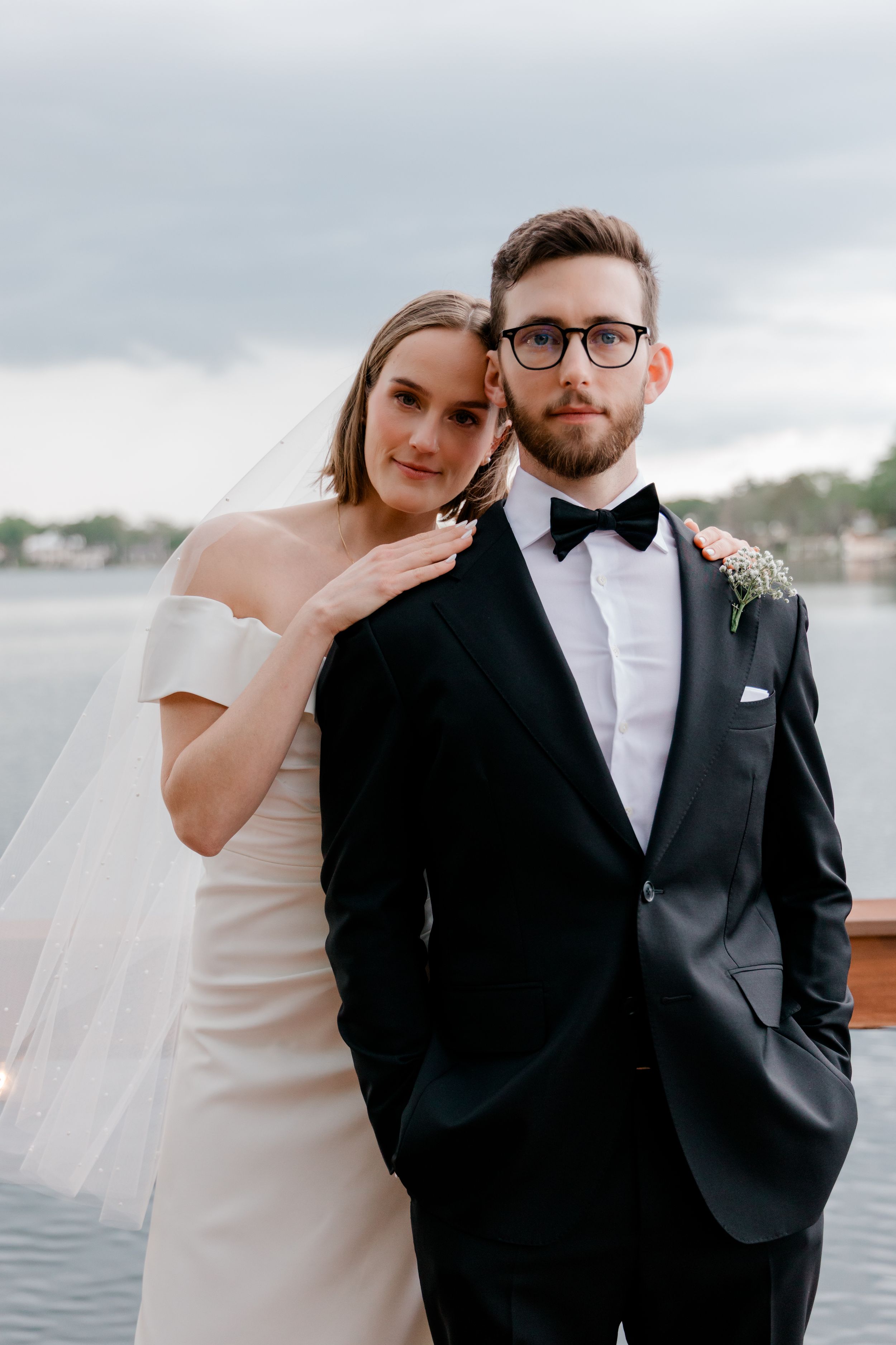 A romantic wedding couple poses next to a vintage white car at sunset.