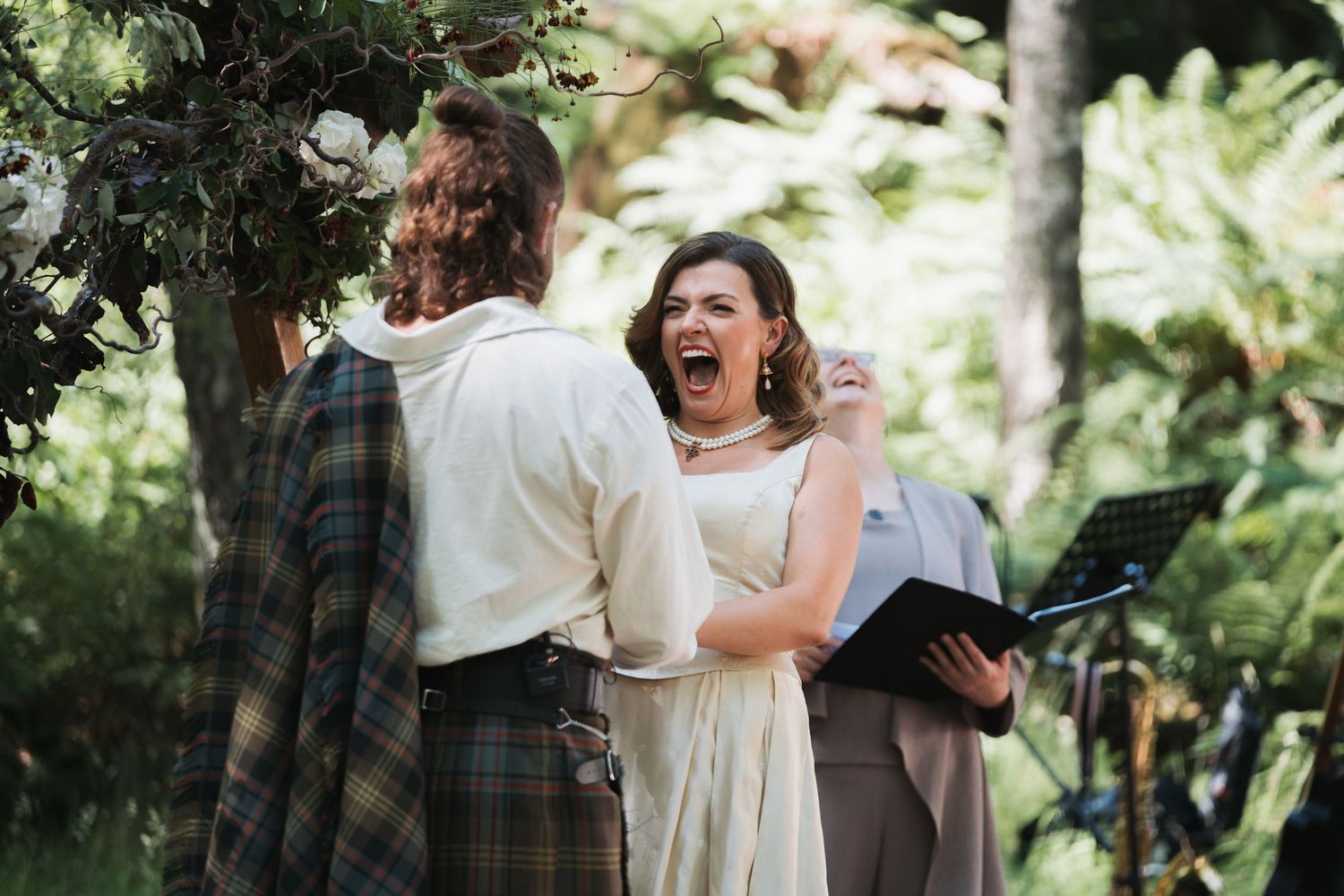 A candid black and white photo of wedding guests laughing and socializing during an outdoor reception.