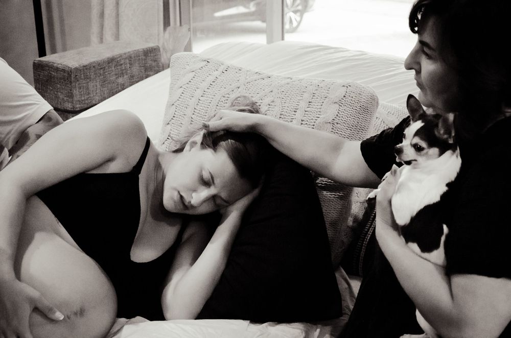 Intimate black and white photo showing support during labor in a home environment.