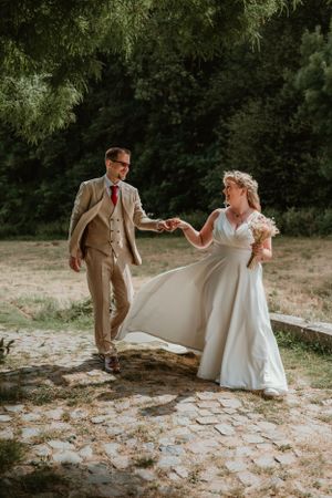 Een koppel in huwelijkskleding danst samen in een natuurlijke buitenomgeving in het park van Kasteel Ter Rijst, foto door Lien Photography