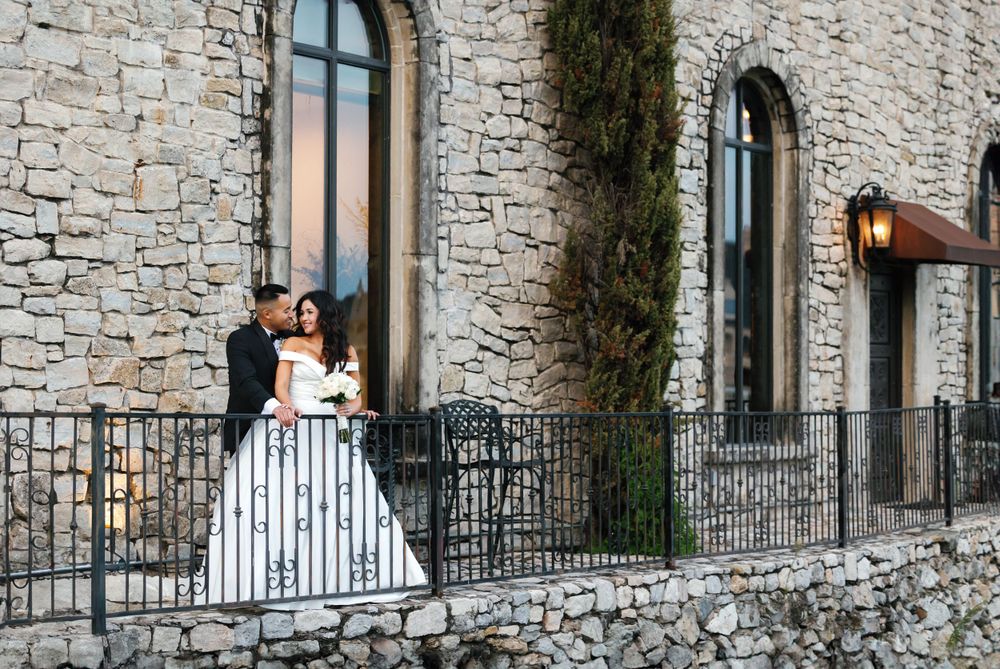 A couple poses on a stone balcony of Adriatica during their wedding.