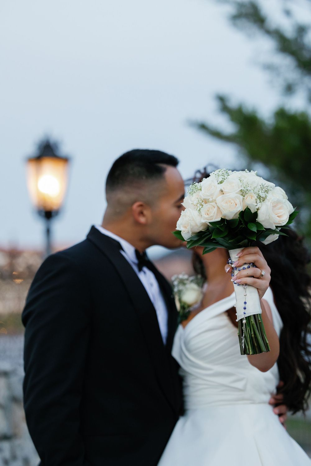 Romantic sunset portrait with white rose bouquet and vintage street lamp.