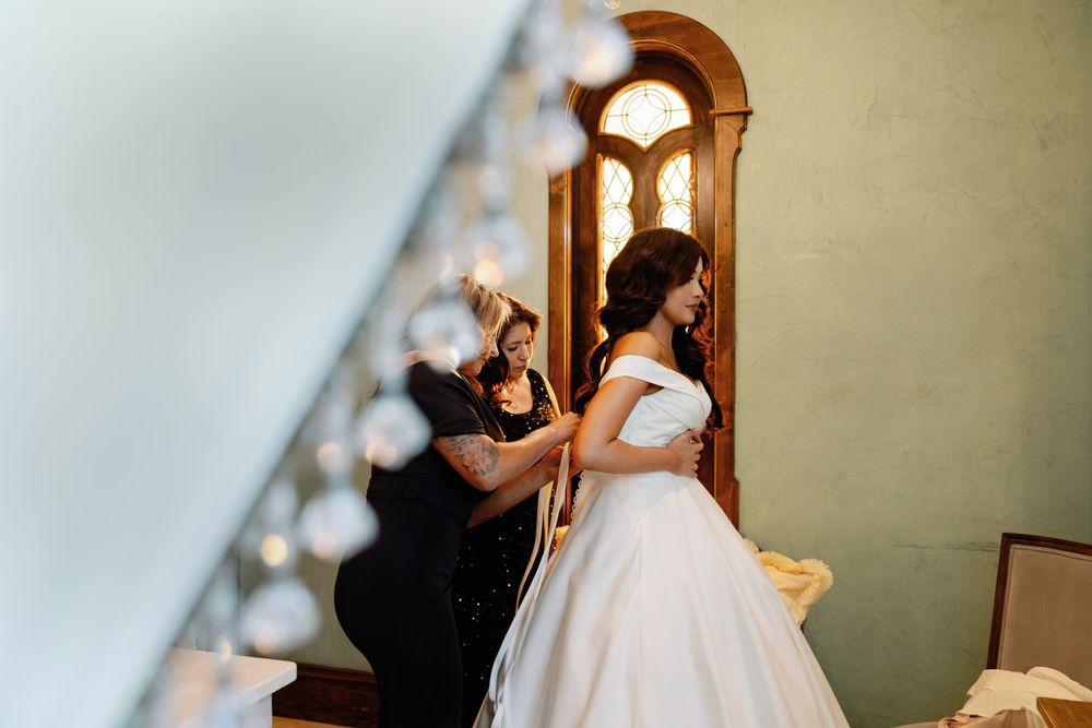 Wedding preparation scene with bride getting dressed in elegant room with arched window