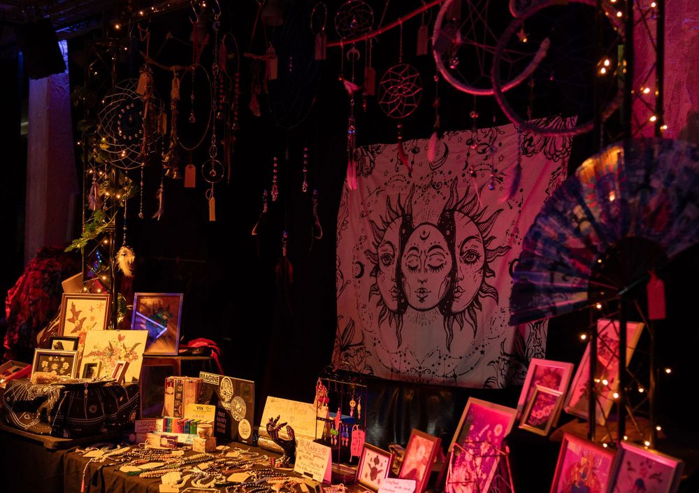 Handmade jewelry or art display on a table at a dark festival or market booth.