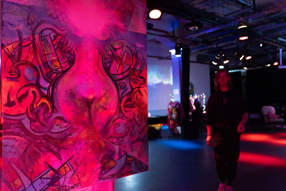 art gallery with a neon painting of a woman and a man in the background