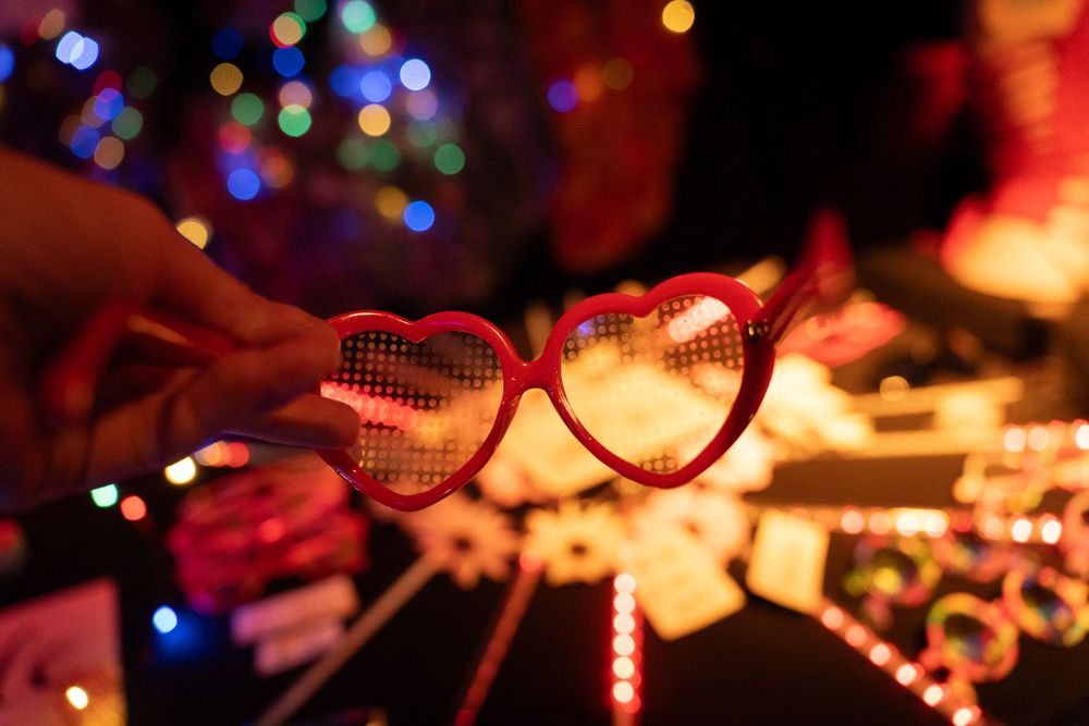 Close-up of flashing LED light-up rave glasses and toys on a table at a dark event.