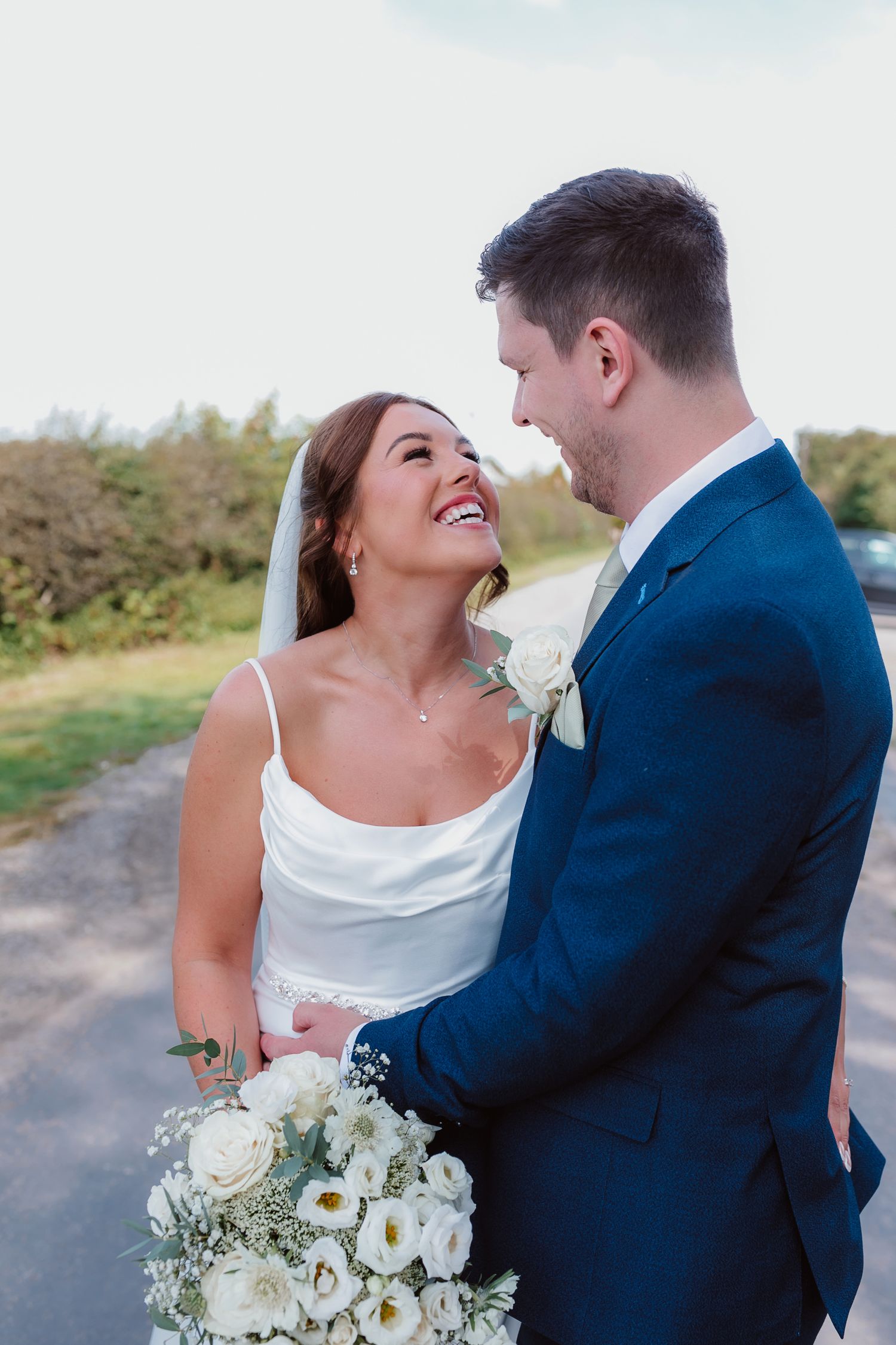 Happy couple shares romantic moment with white floral bouquet on country path. Photographer. Hull. East Yorkshire. Photography