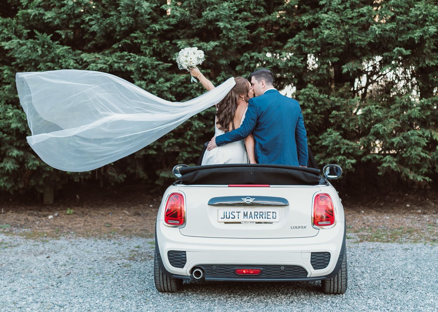 Newlyweds pose on Mini Cooper with flowing veil in countryside setting. Photographer. Hull. East Yorkshire. Photography