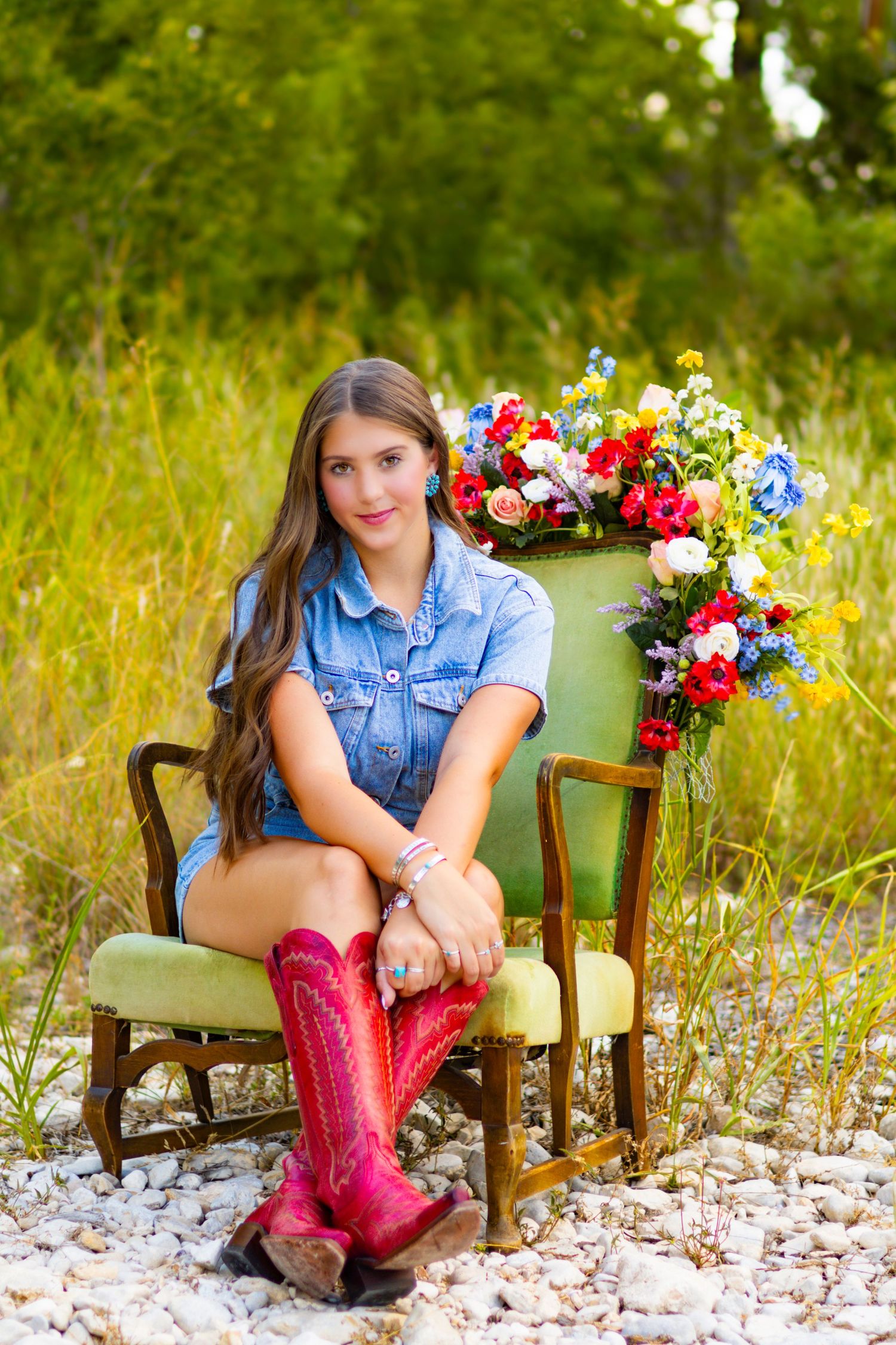 Green velvet chair decorated with colorful flowers and pink rain boots in an outdoor setting.