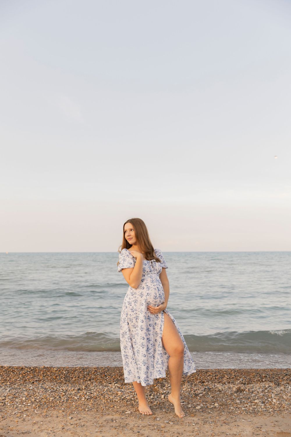 pregnant woman standing on the beach of Lake Huron holding her belly