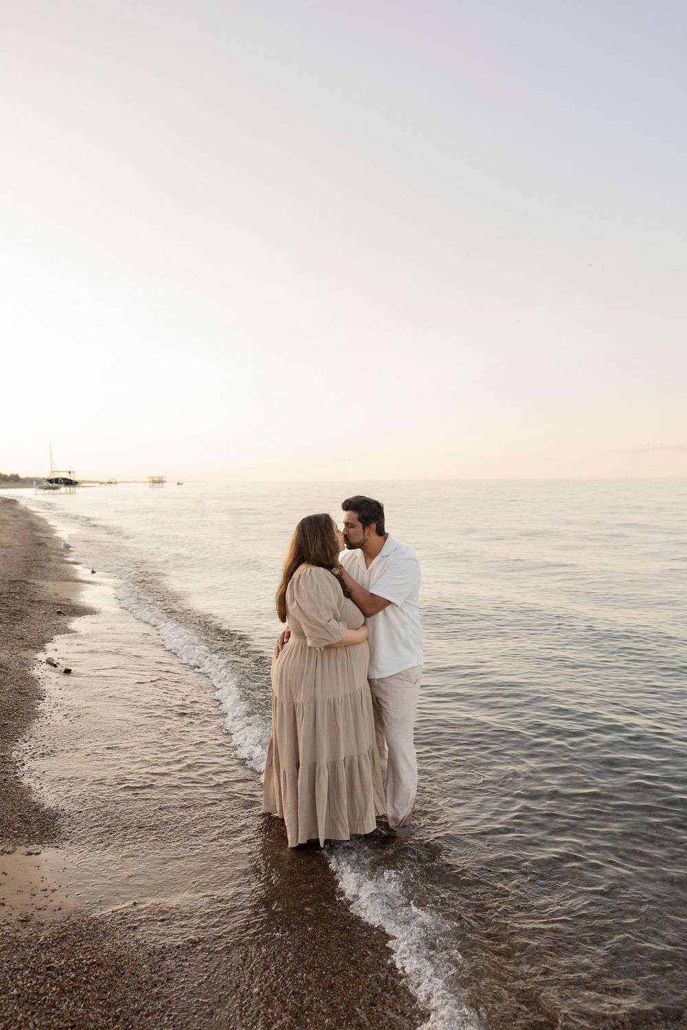 Pregnant couple sharing intimate moments at the seashore during sunset while walking together along the beach.