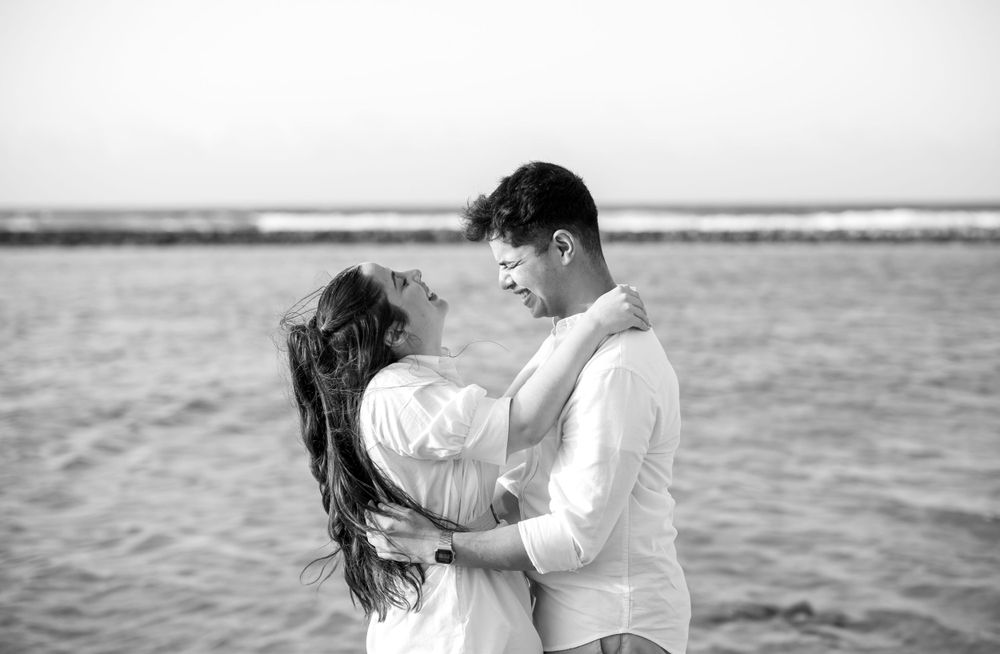 Black and white portrait of couple sharing intimate moment by the ocean.