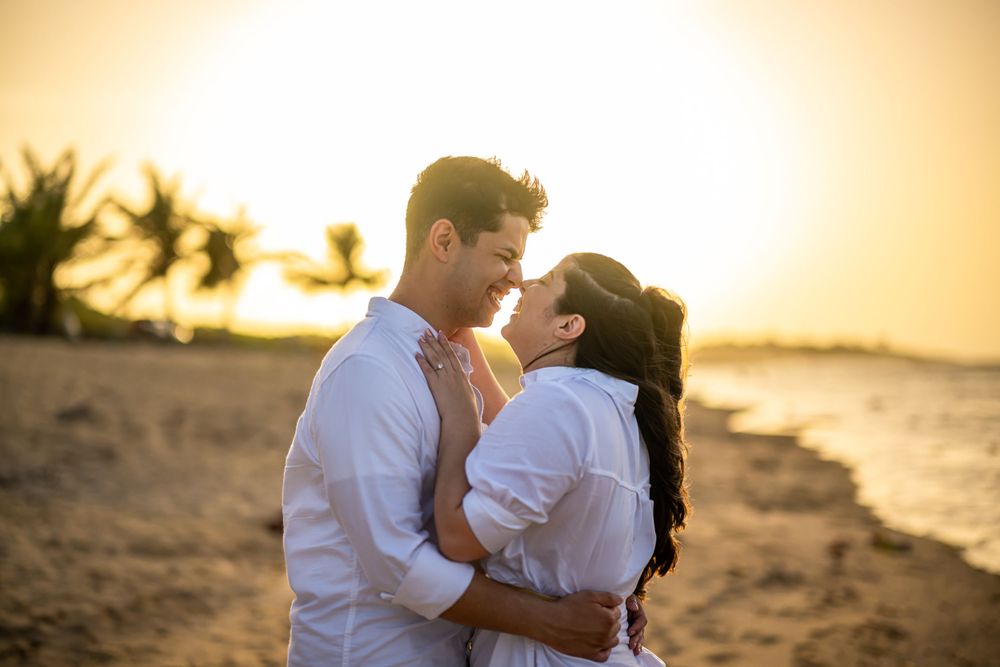 A tender beachside moment captured during golden hour with palm trees silhouetted against the sunset.