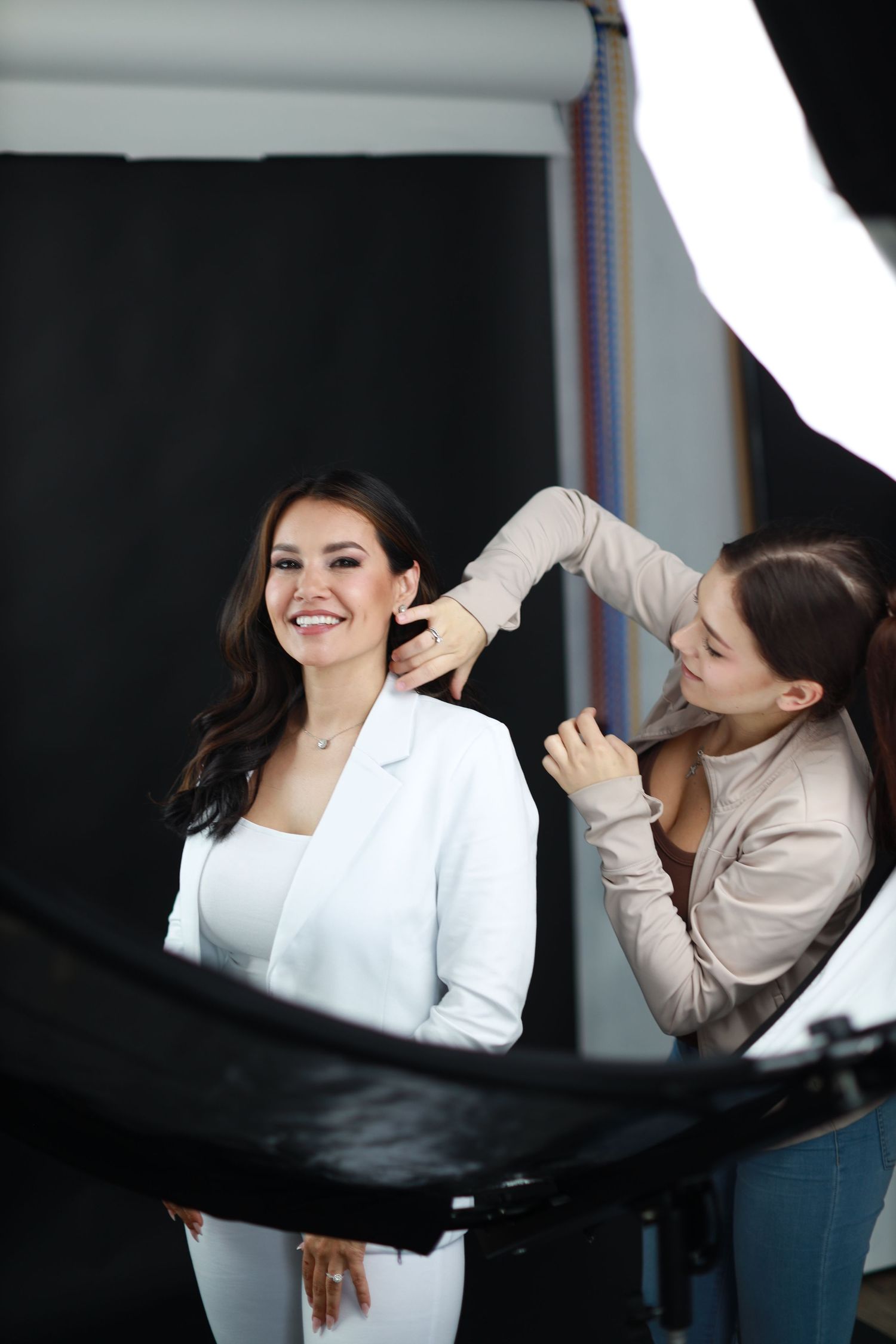 Behind the scenes photo of hair stylist working with model during professional photoshoot.