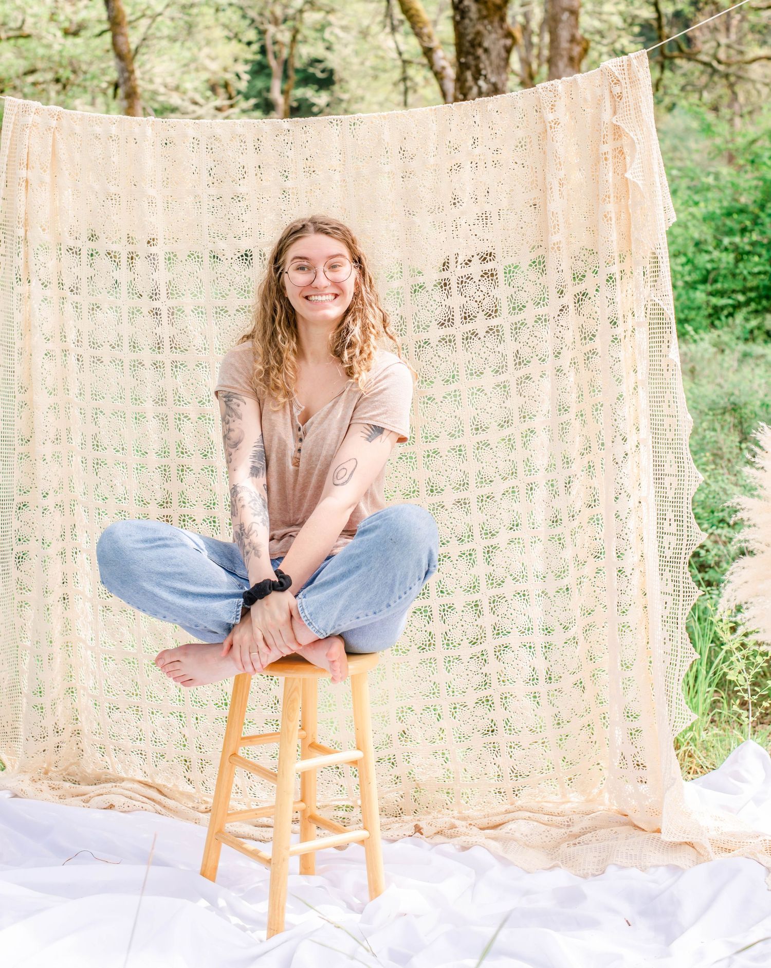 Natural light photography setup with cream lace backdrop and wooden stool on white fabric.